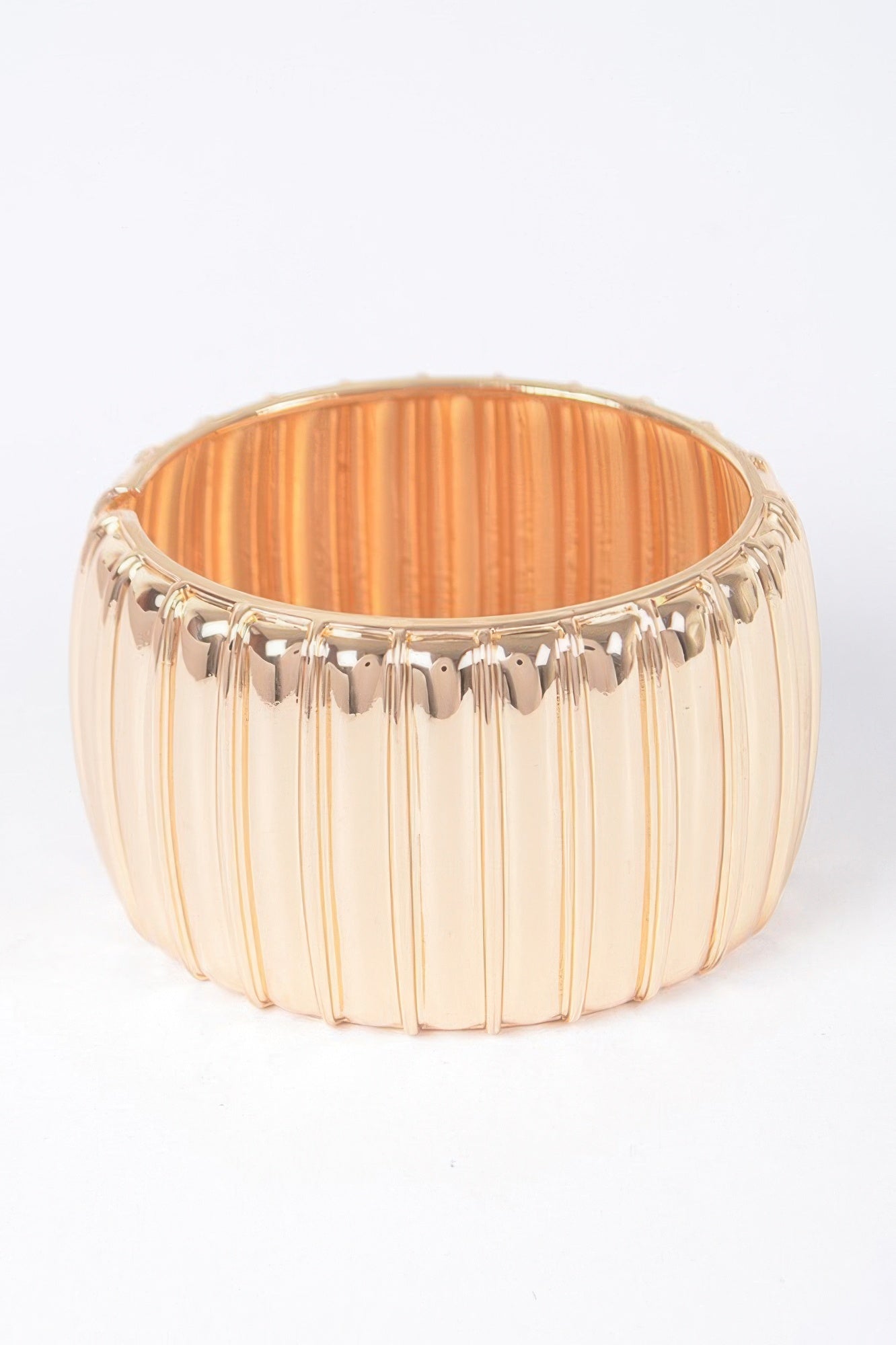 Gold textured metal bangle with vertical ridges and scalloped front edge