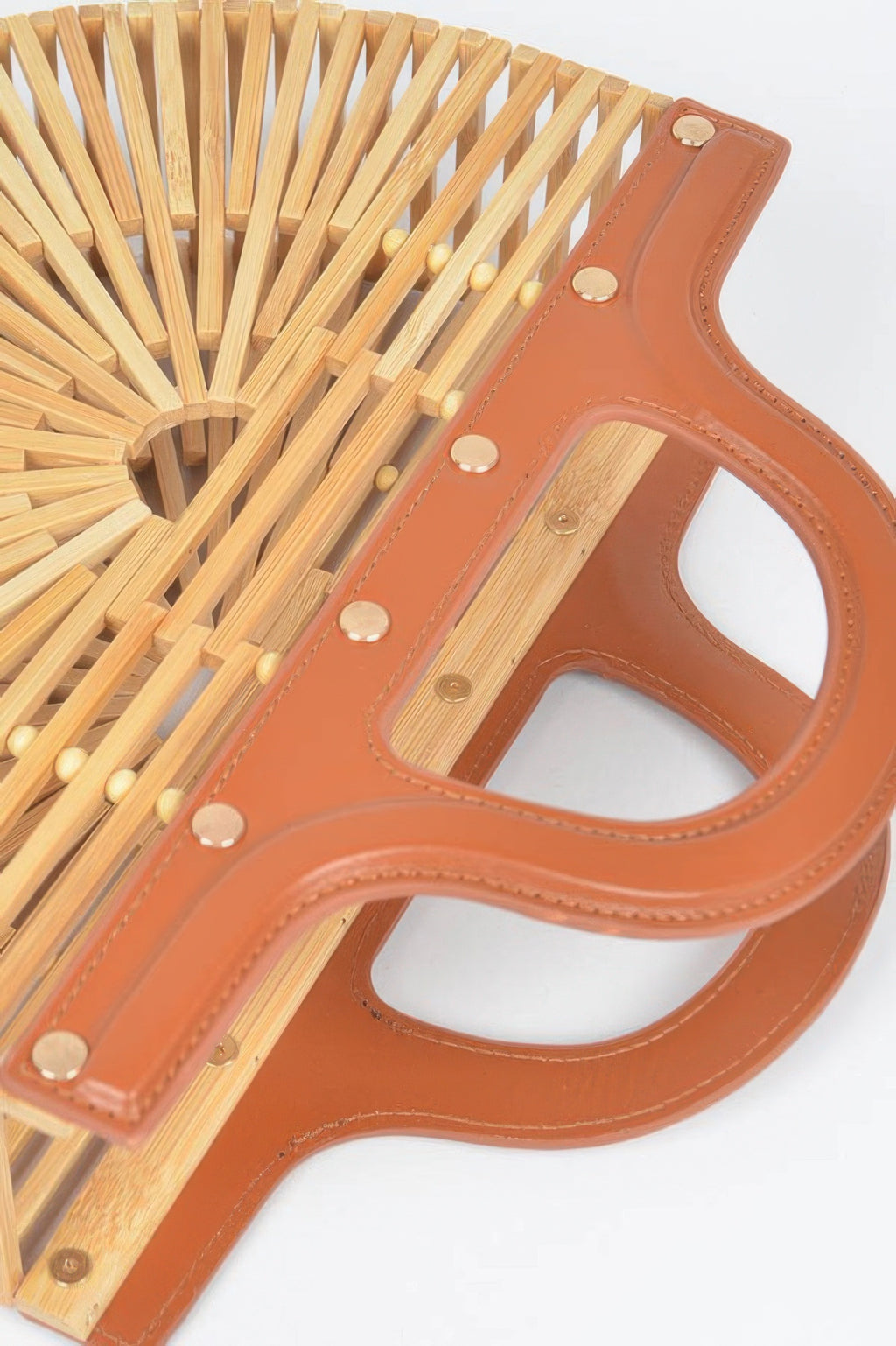 Close-up of bamboo top-handle bag: caramel leather strap with gold snaps on slats