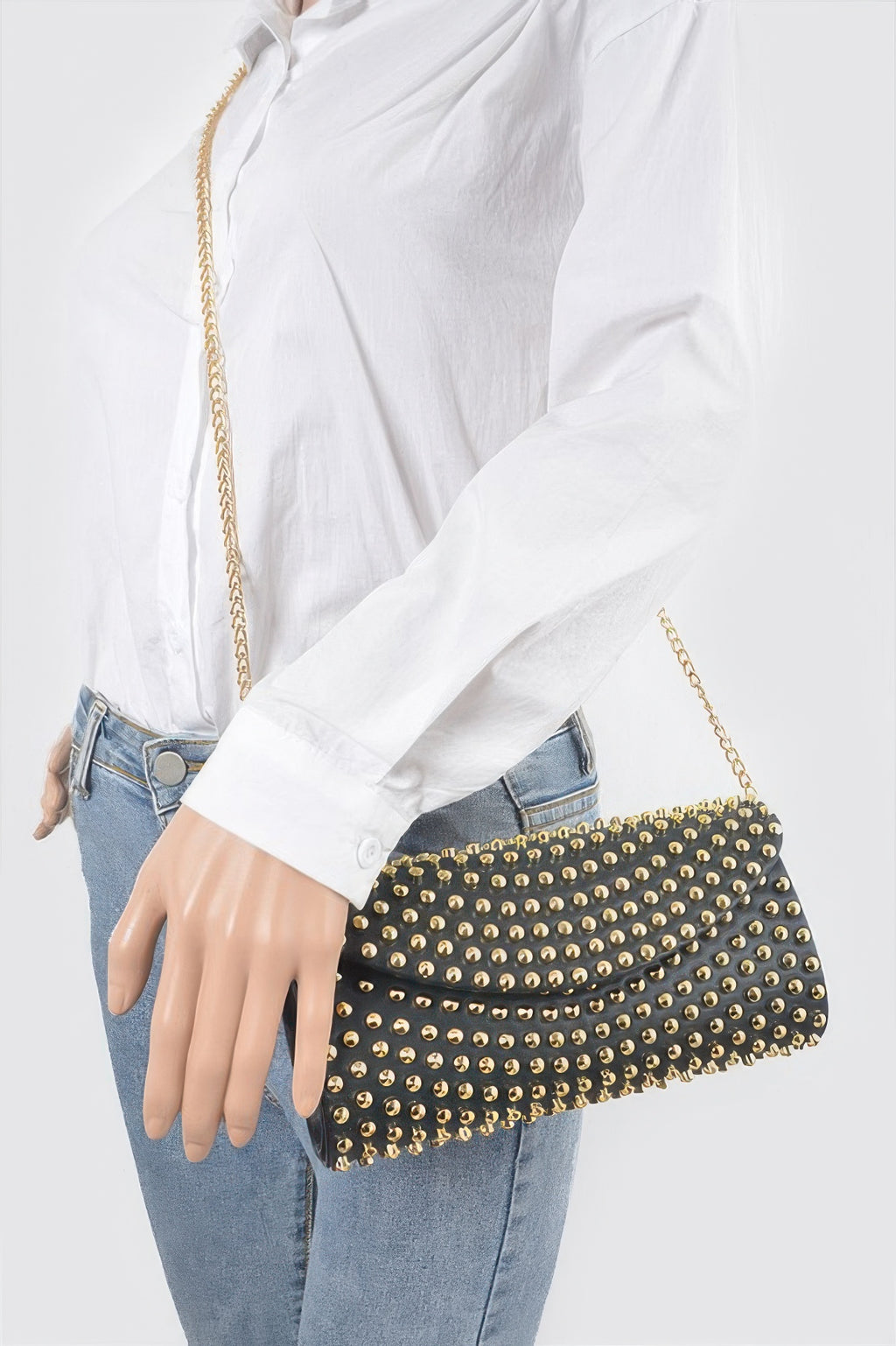 Black studded clutch worn crossbody with gold chain strap