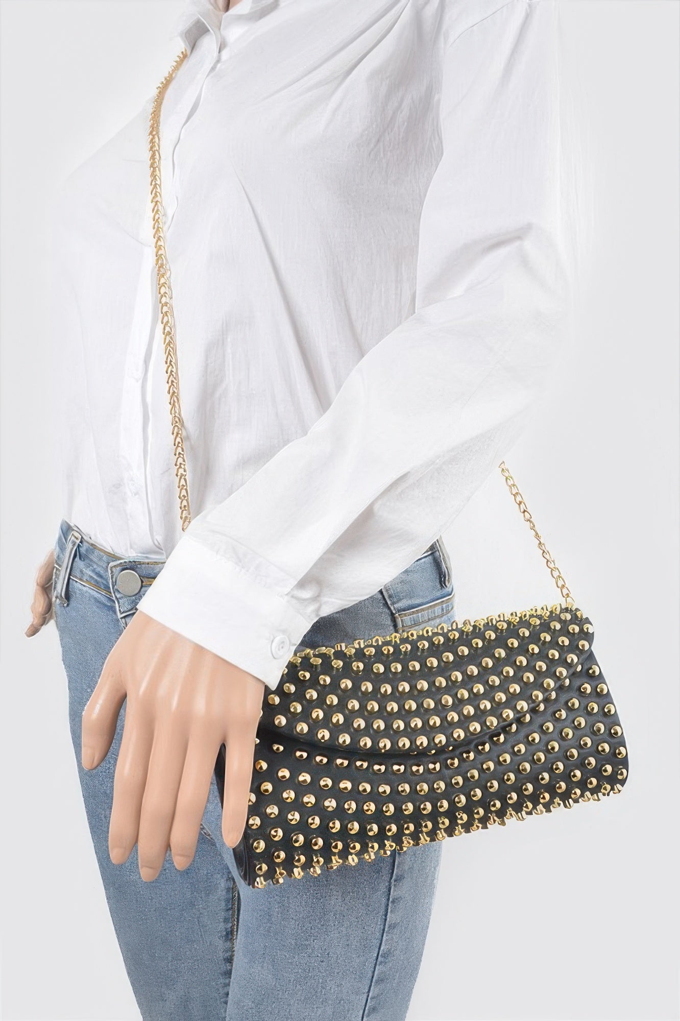 Black studded clutch worn crossbody with gold chain strap