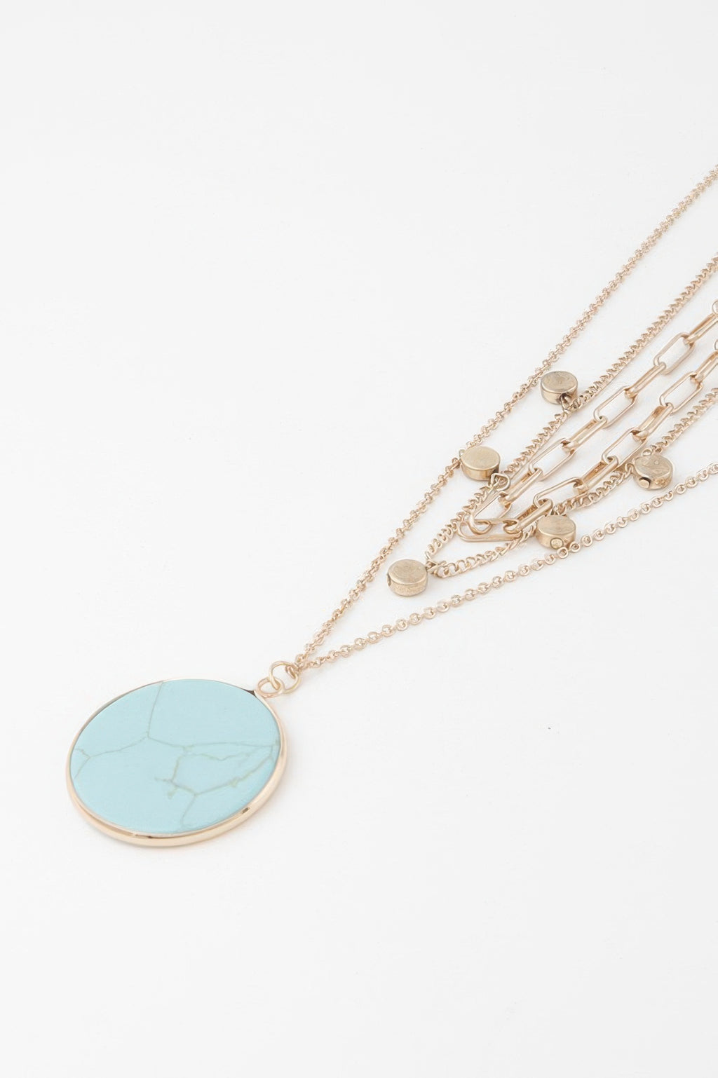 Close-up of gold layered chains with round turquoise disc pendant