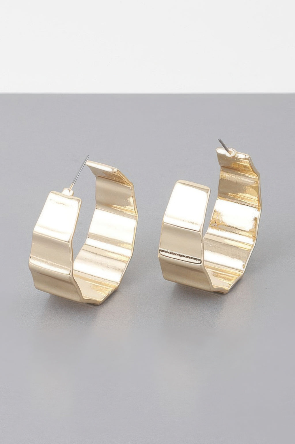 Gold ribbed hoop earrings close-up, textured metal cuff with ear wires