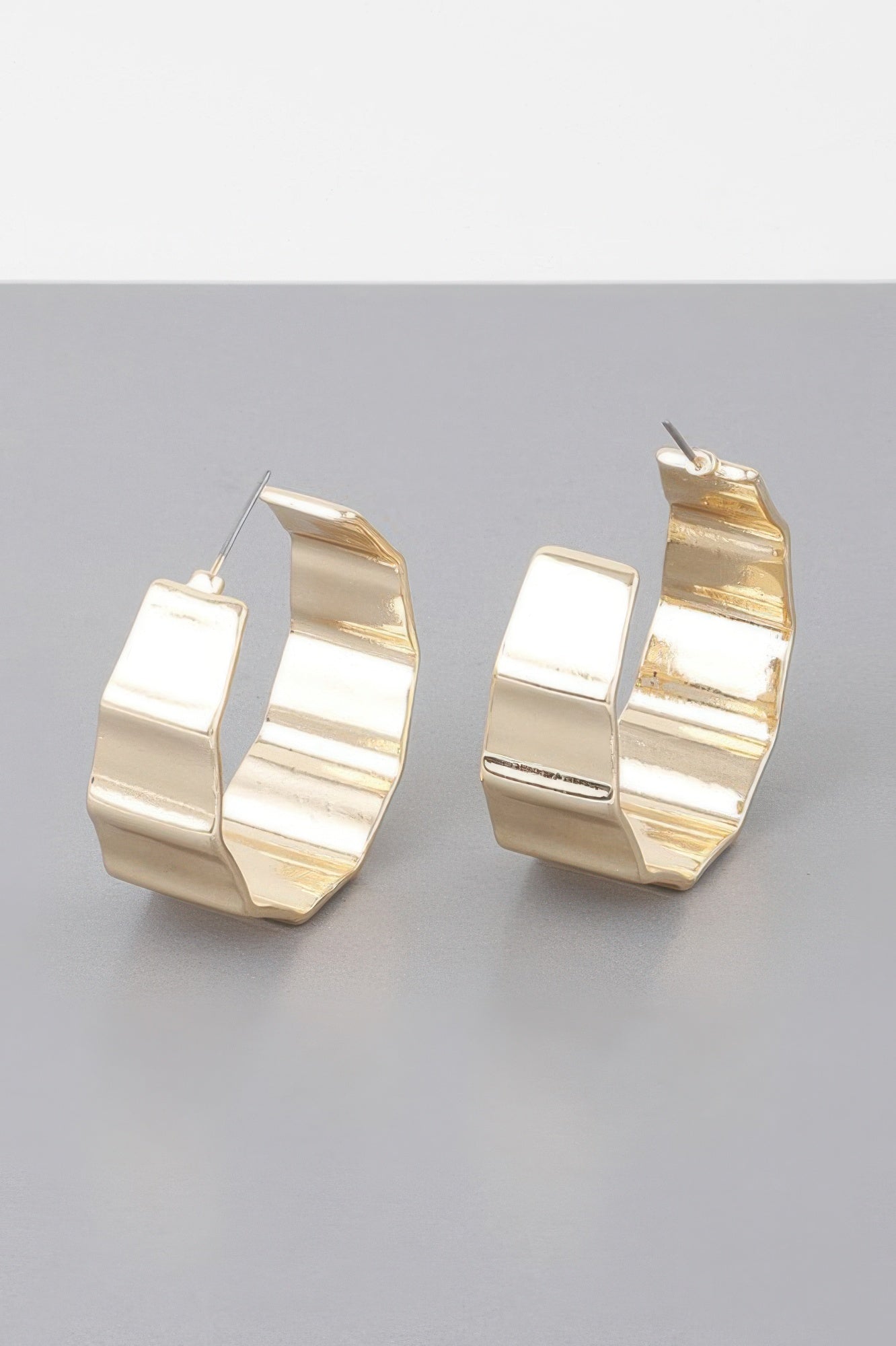 Gold ribbed hoop earrings close-up, textured metal cuff with ear wires