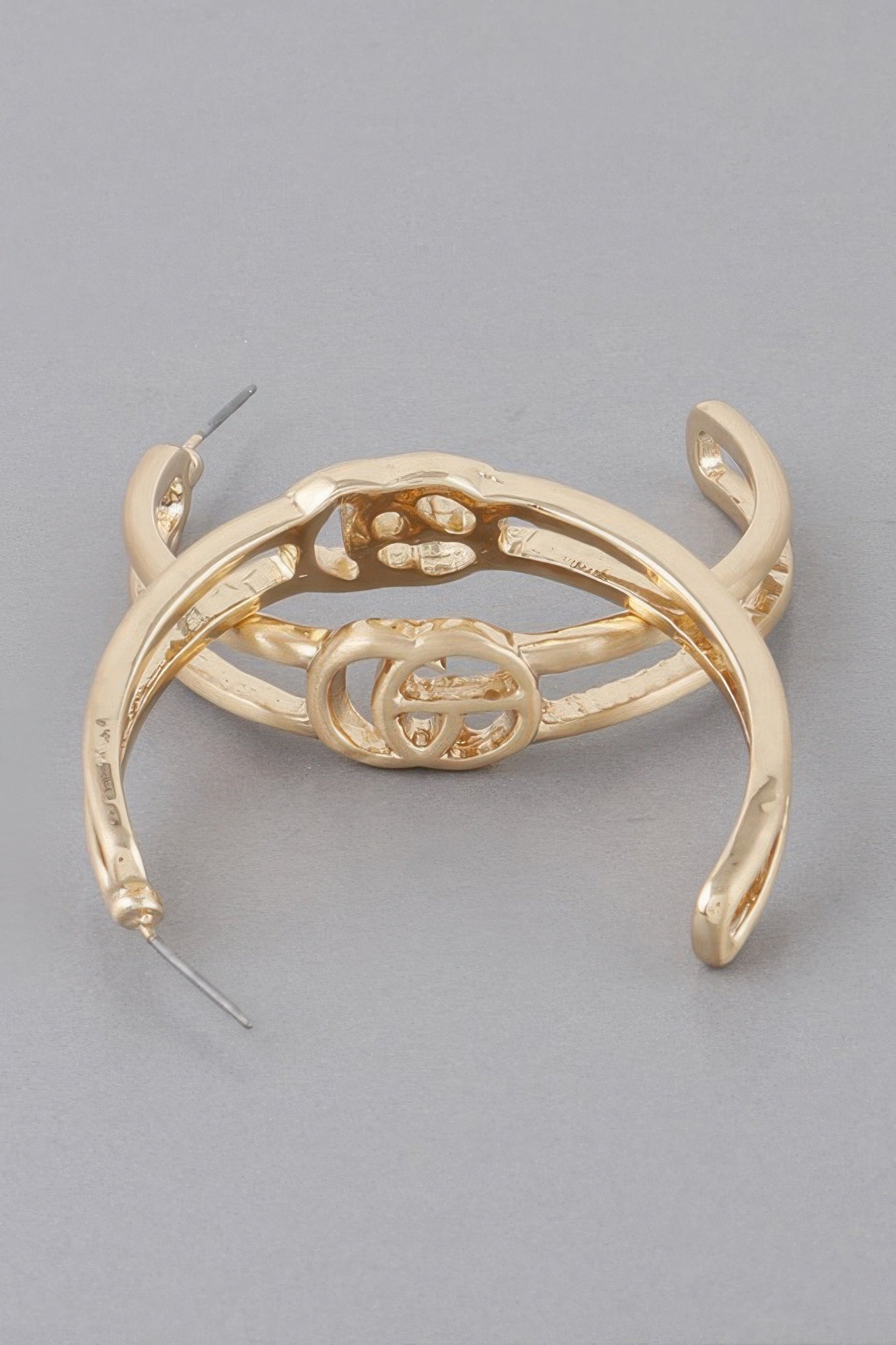 Gold Cg hoop earrings, close-up of inner emblem and curved hoop.