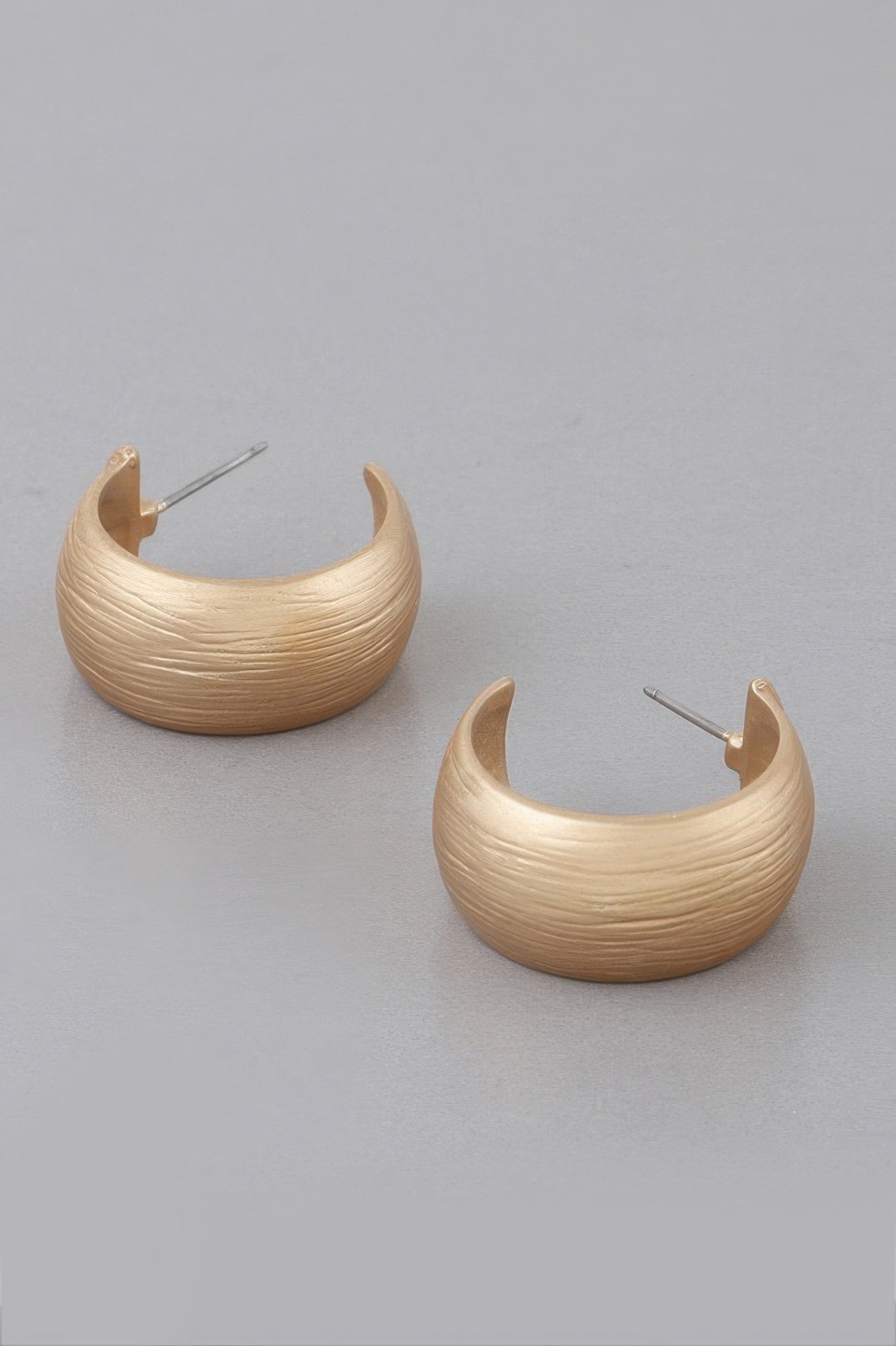 Scraped bulky hoop earrings with gold-tone finish, stud posts visible