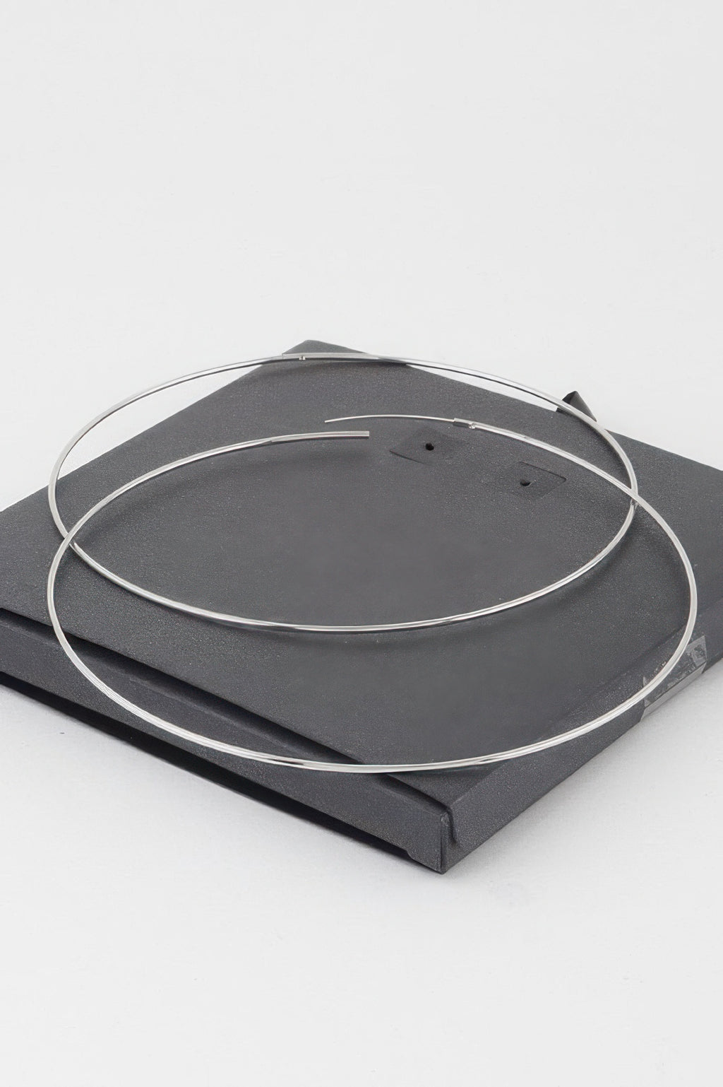 Silver wide hoop earrings laid flat on a display card