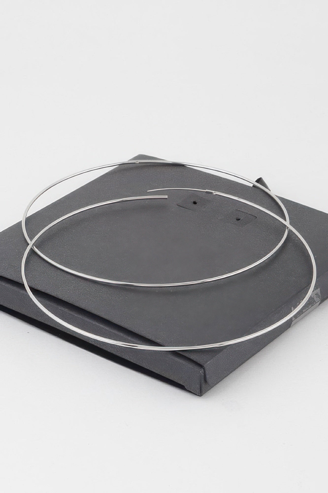 Silver wide hoop earrings laid flat on a display card