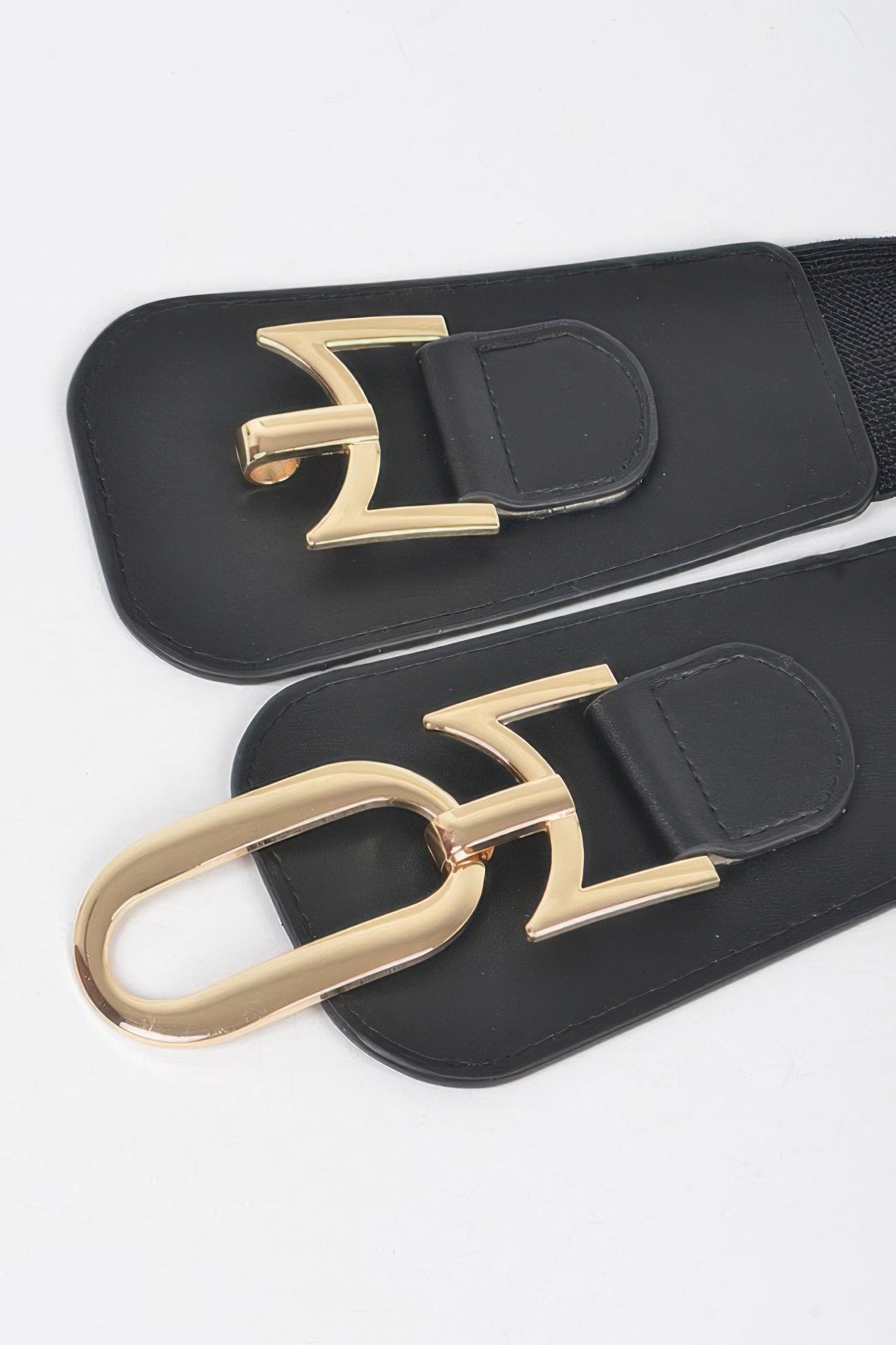Close-up: black elastic belt with gold buckle, oval clasp and stitched belt tabs