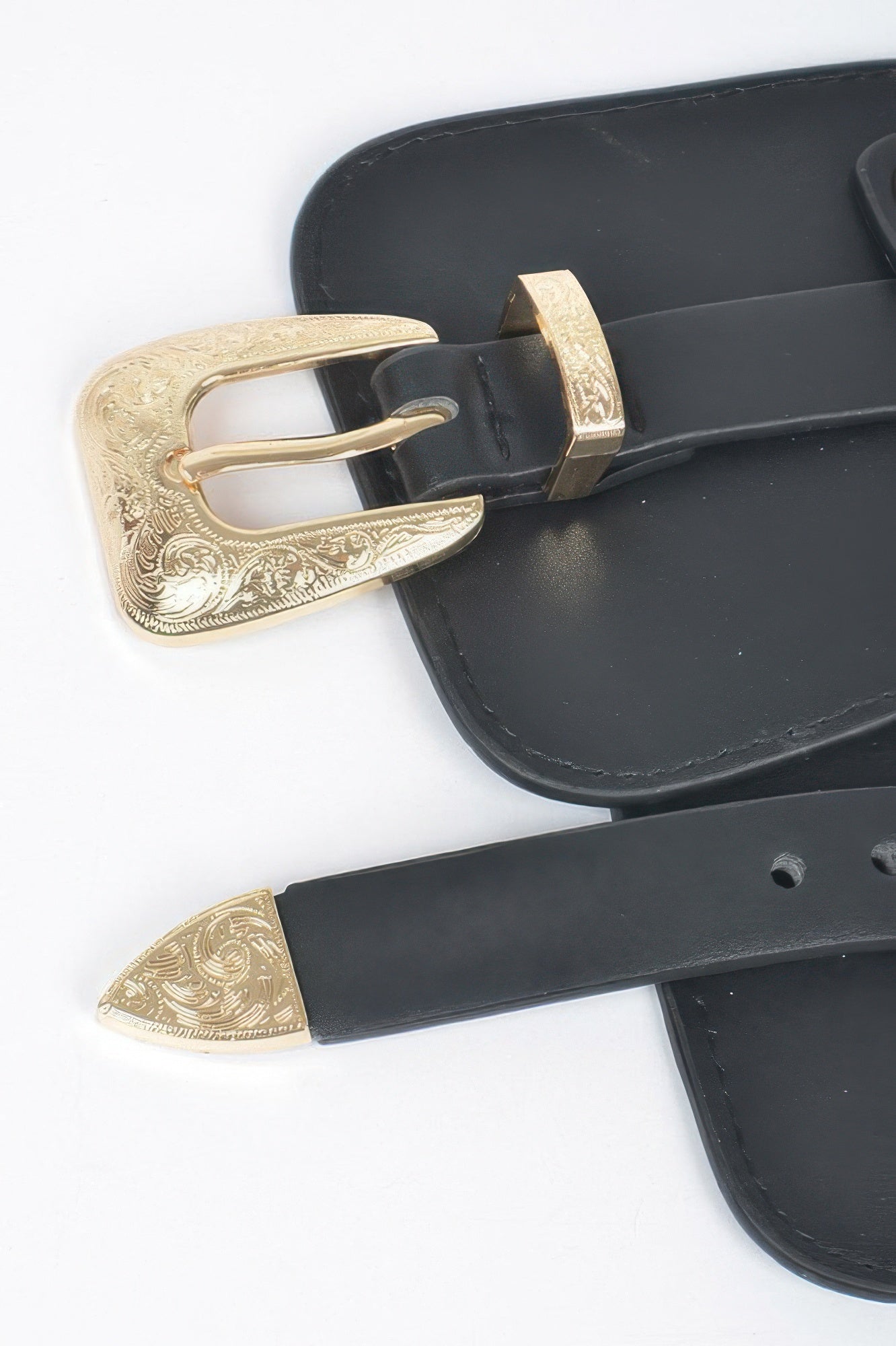 Close-up of black belt with ornate gold buckle and stitched trim
