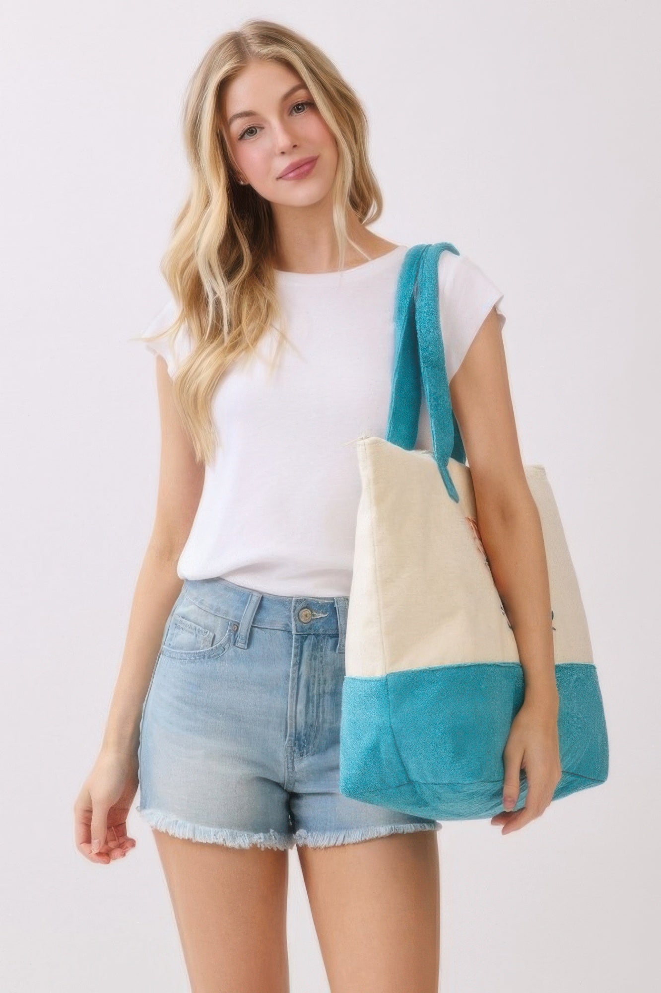 Tote de playa bicolor: parte superior crema y base azul, con asas de tela turquesa.
