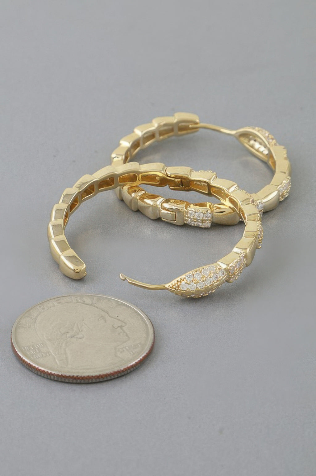 Gold snake-scale hoop earrings with raised link texture and clear crystal details