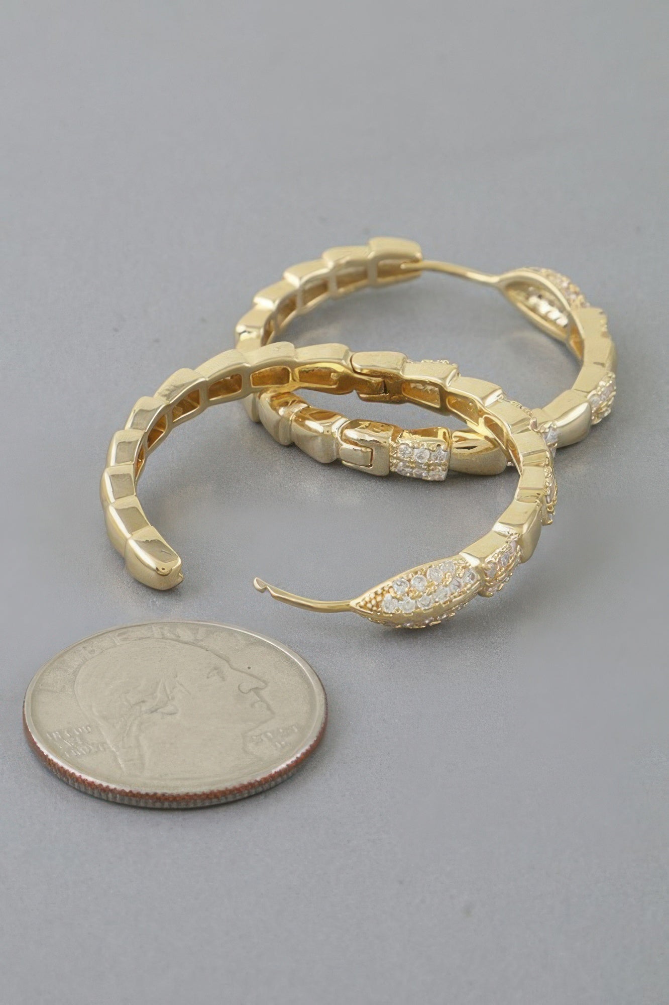 Gold snake-scale hoop earrings with raised link texture and clear crystal details