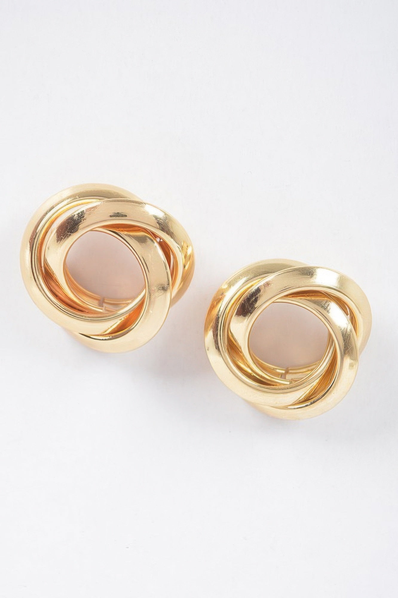 Gold metal stud earrings with twisted circular knot design