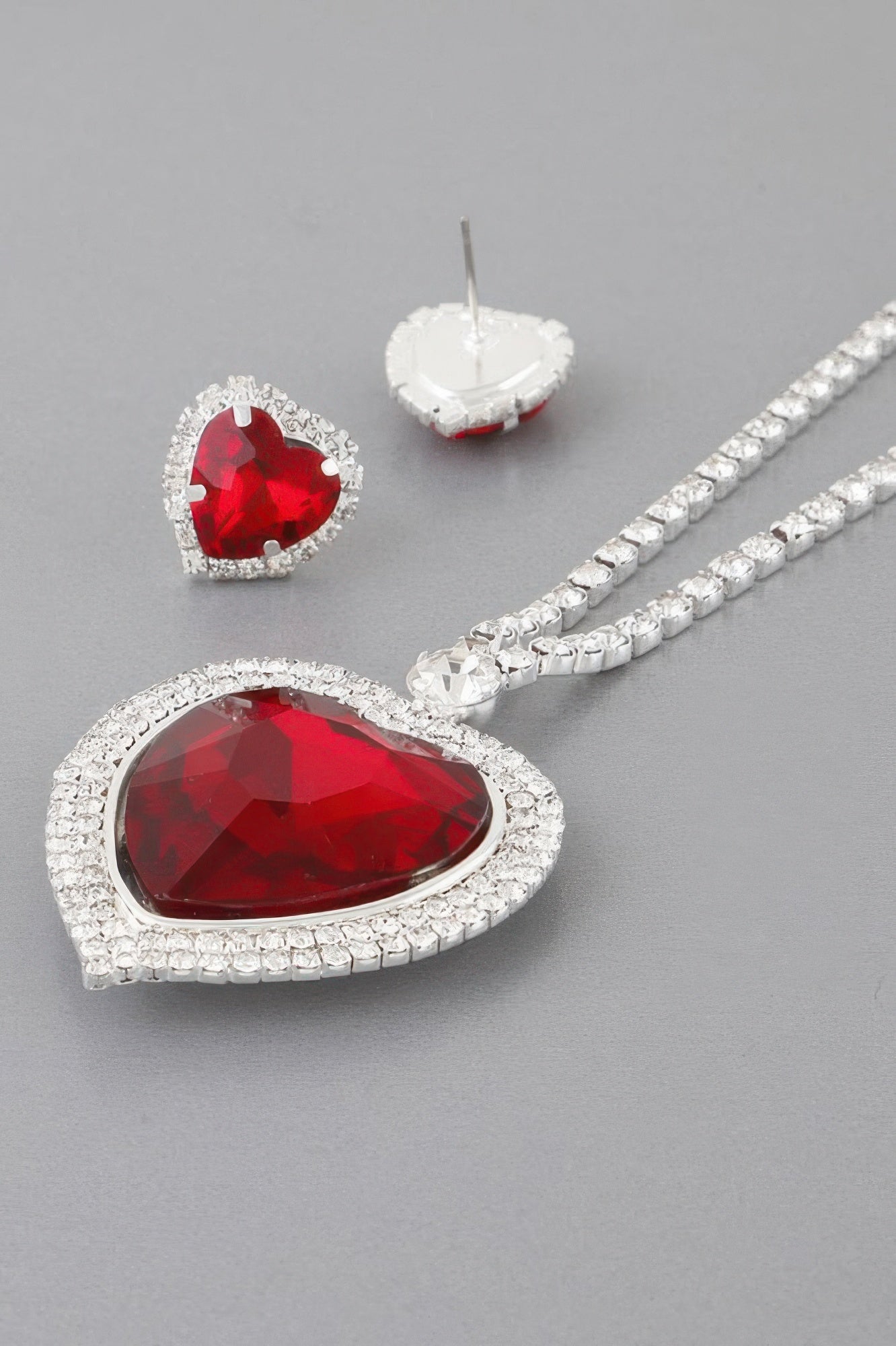 Silver necklace with large red faceted heart pendant and small red stud earring