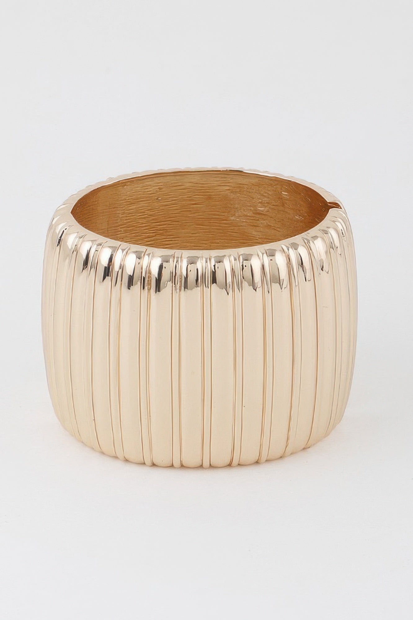 Wide ribbed cuff bracelet in gold, rounded open band.