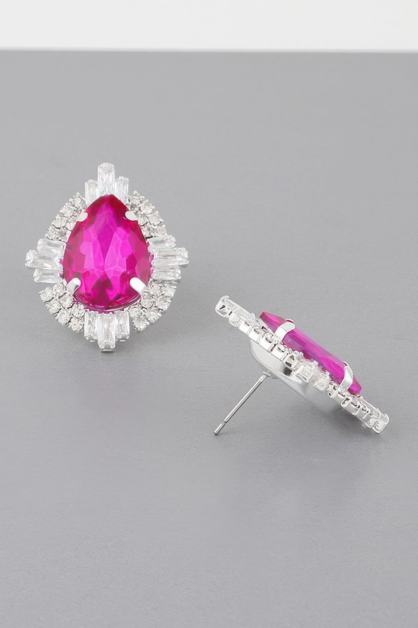 Fuchsia teardrop crystal stud earrings with silver-toned prong setting, side view