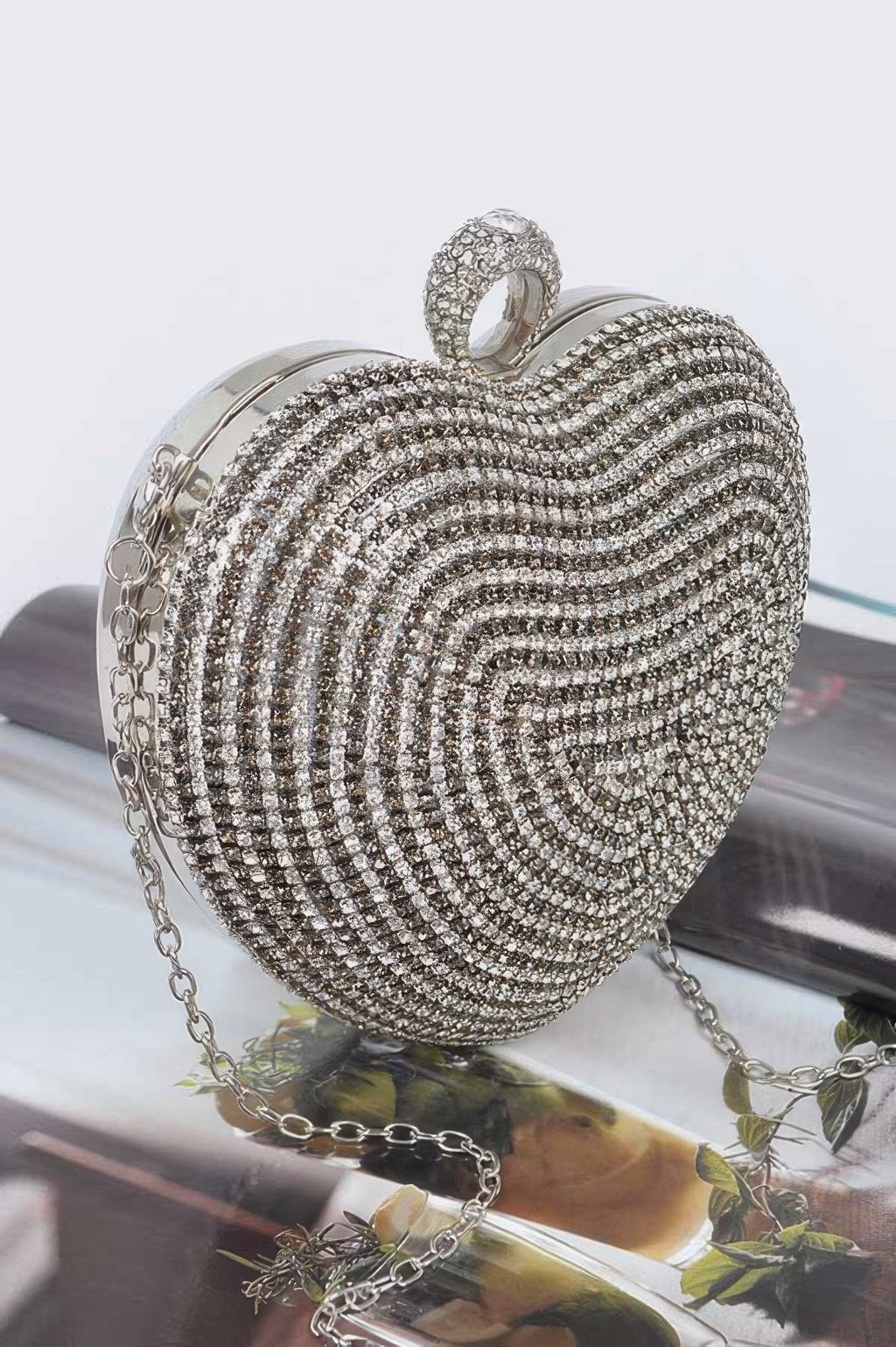 Silver rhinestone heart clutch bag with chain strap and decorative charm on front loop