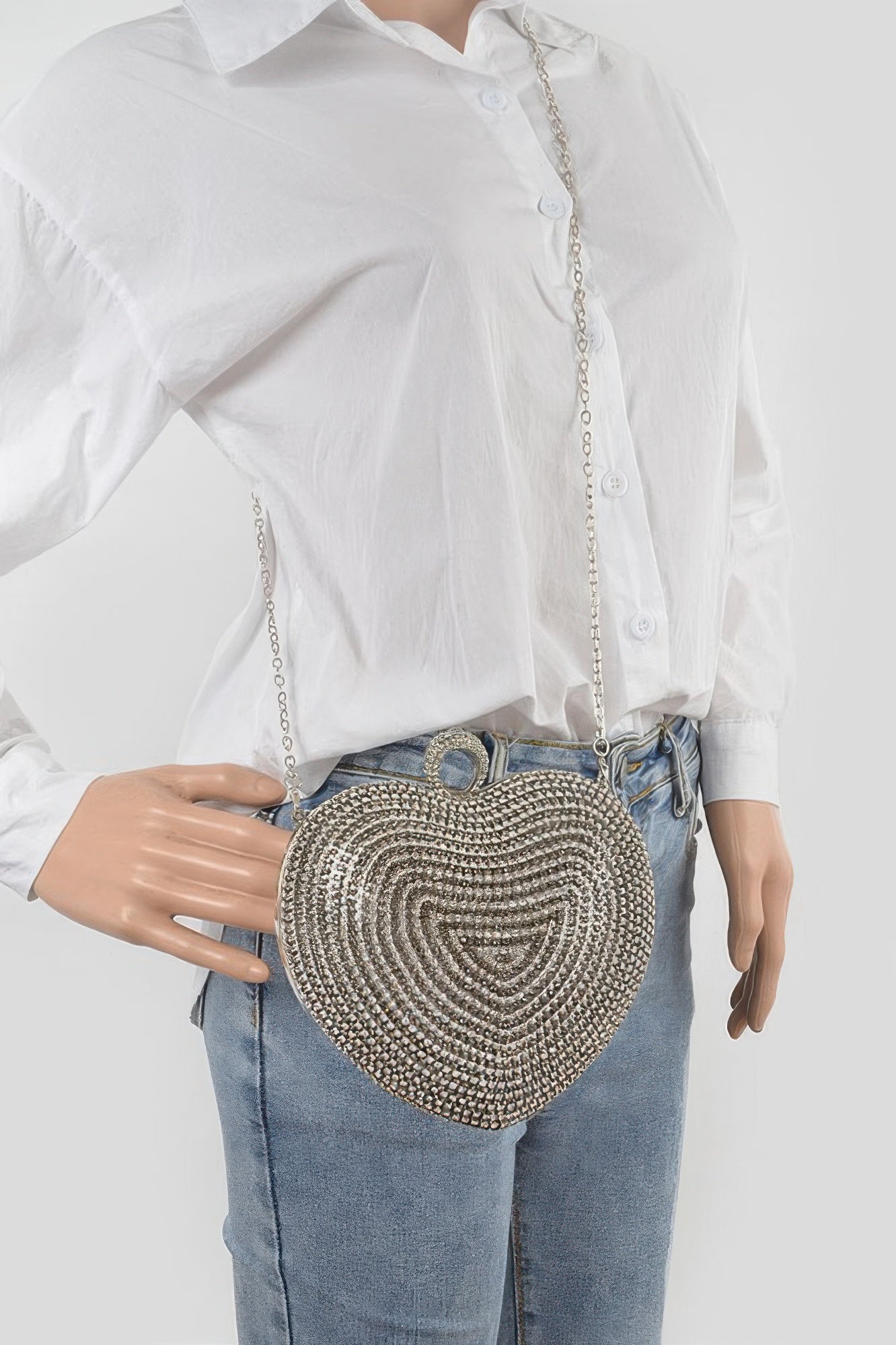 Rhinestone heart clutch on model with long chain strap over light blue jeans, silver-tone