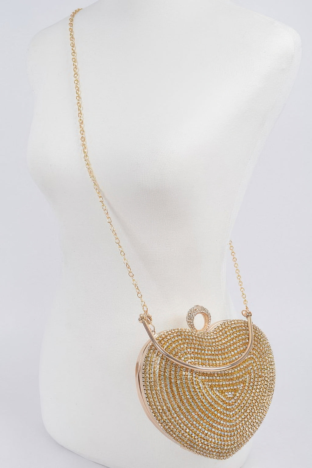 Gold-tone rhinestone heart crossbody clutch with long chain strap on mannequin