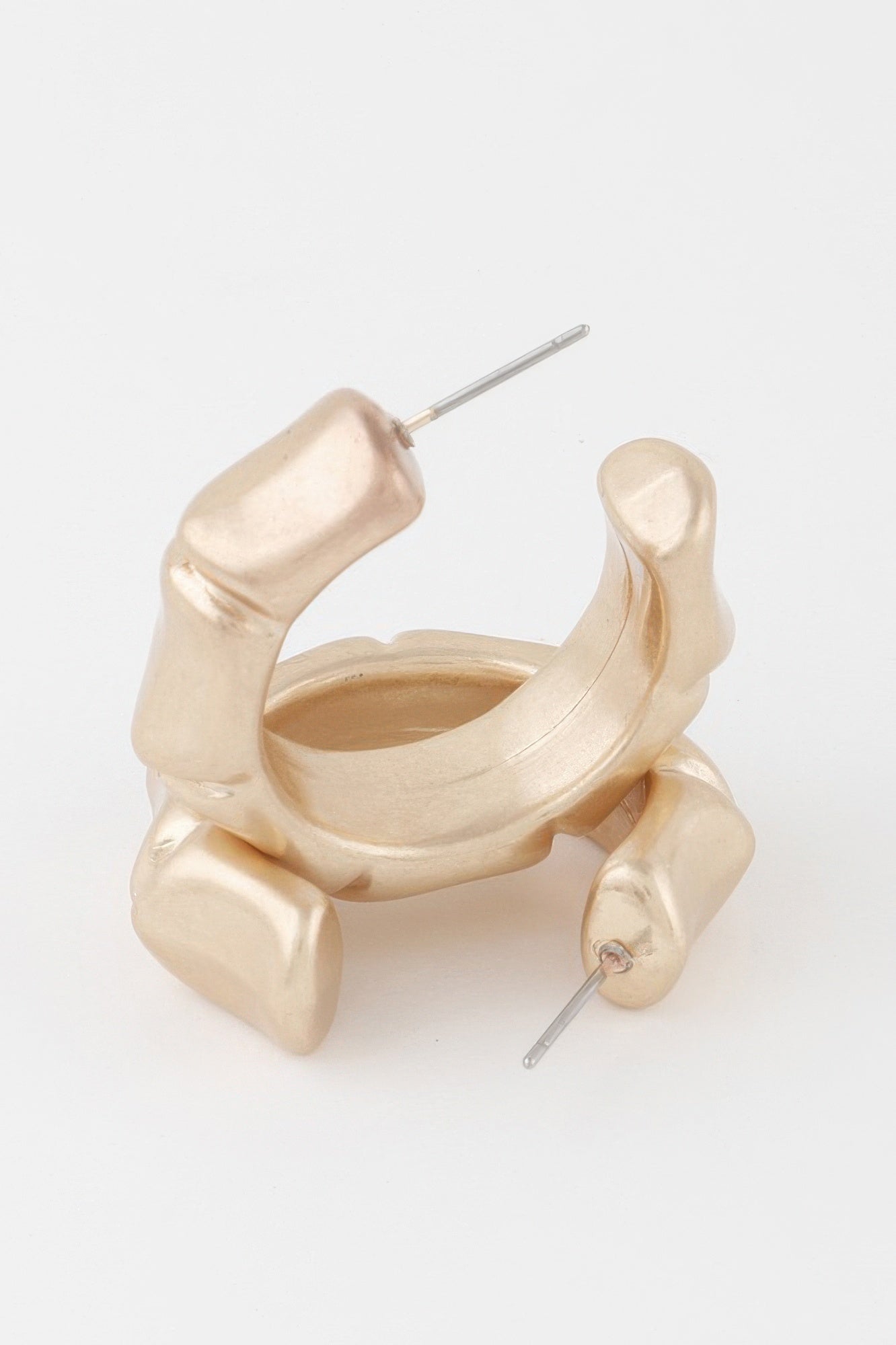 Close-up: gold skeleton-style hoop earrings with attached stud posts