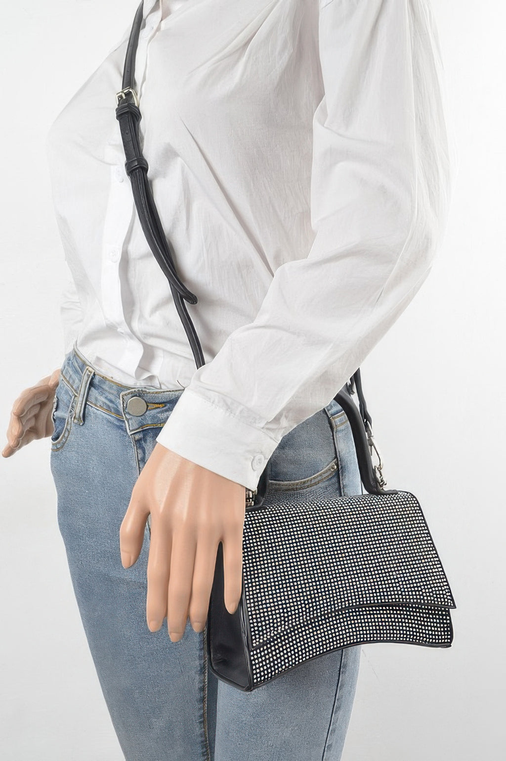 Rhinestone top-handle bag on shoulder with black strap and clear-tone rhinestone flap front