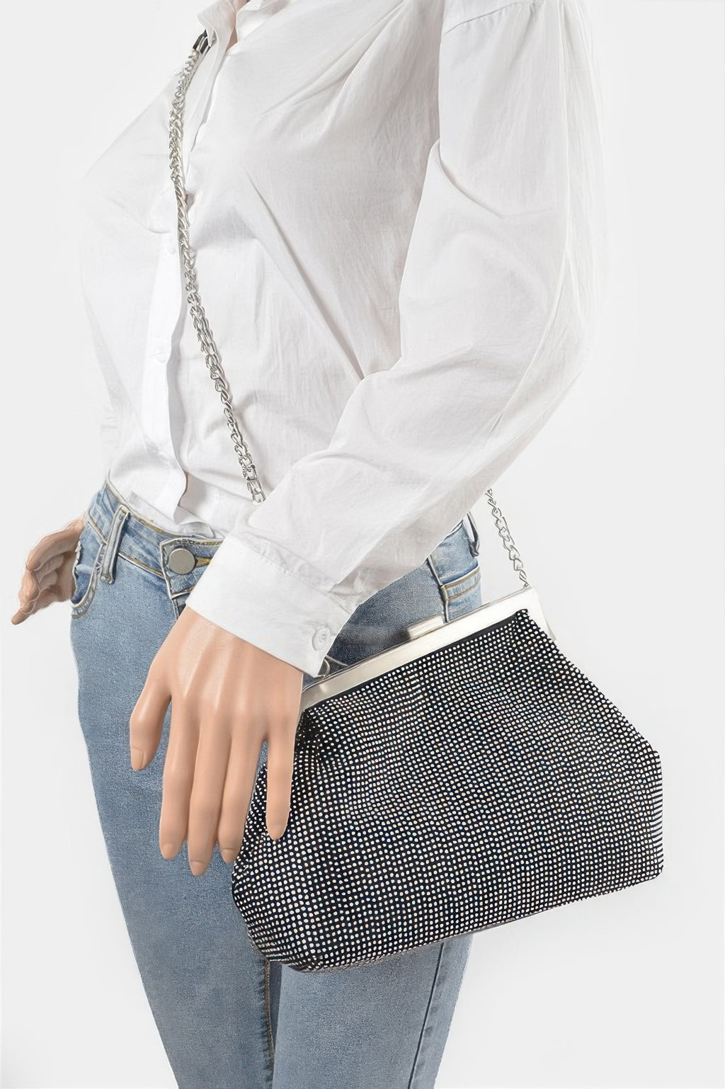 Black rhinestone frame clutch worn crossbody with chain strap over denim jeans