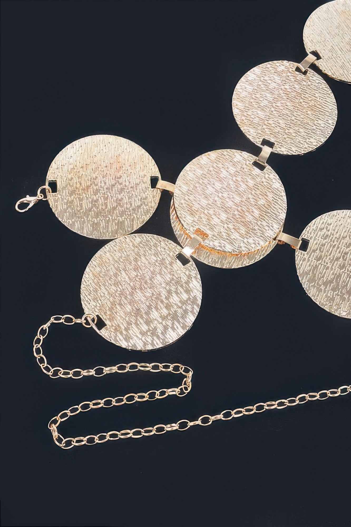 Close-up of gold circular plate belt links with chain and round plate ends
