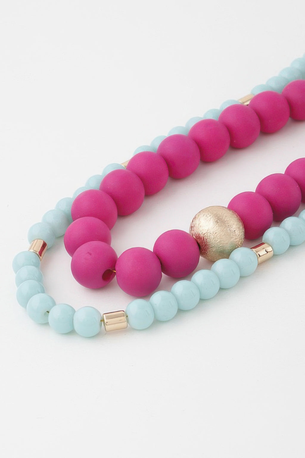 Two-toned beaded long necklace detail: fuchsia pink and light blue beads, gold spacer