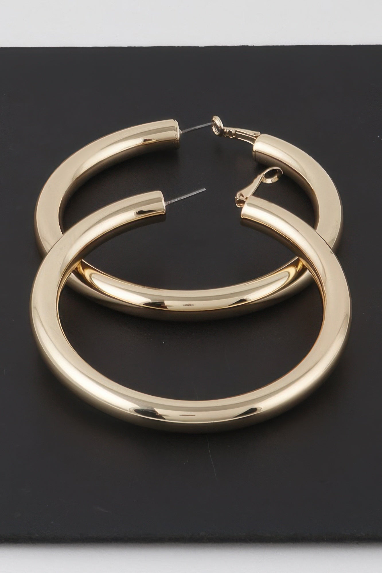 Gold sleek tube hoop earrings with hinged clasp, glossy curved metal rings
