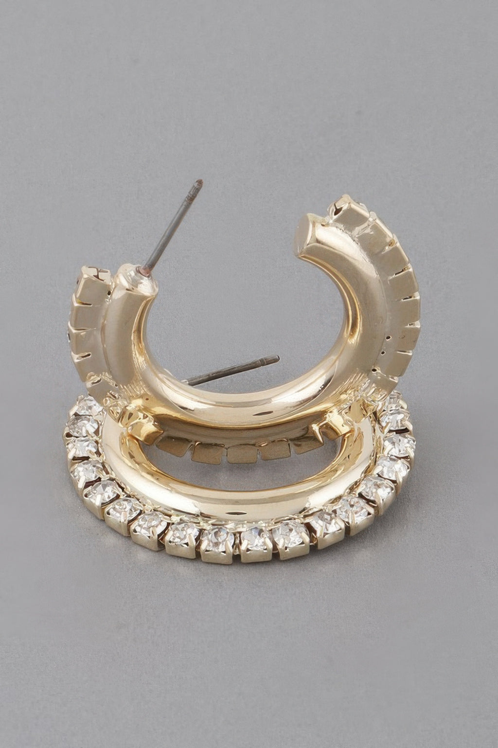 Close-up gold-tone hoop earring with clear stones around the front bezel
