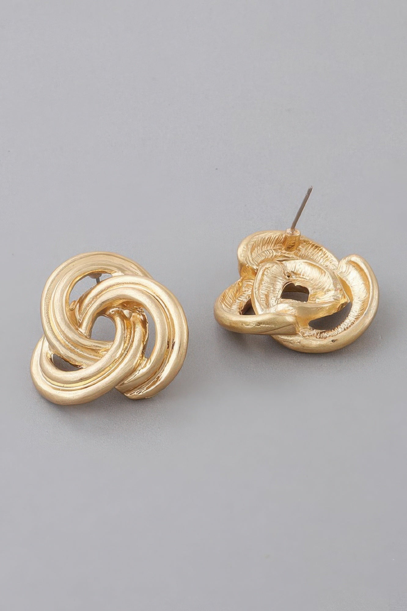 Gold-tone triple knot stud earrings with visible earring posts and swirl detail