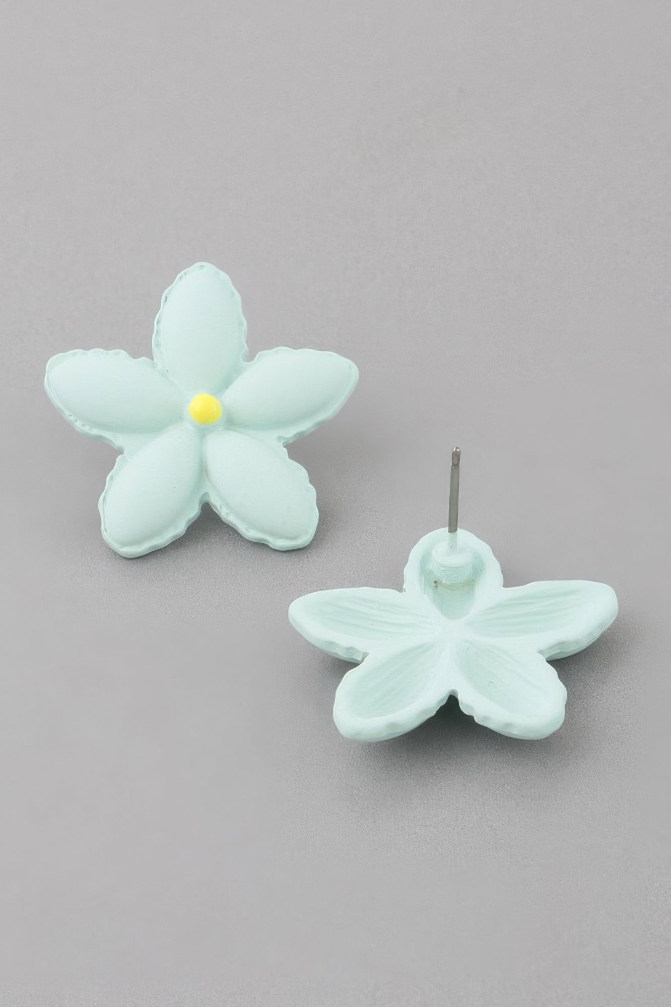 Mint green flower stud earrings with yellow center; metal post visible
