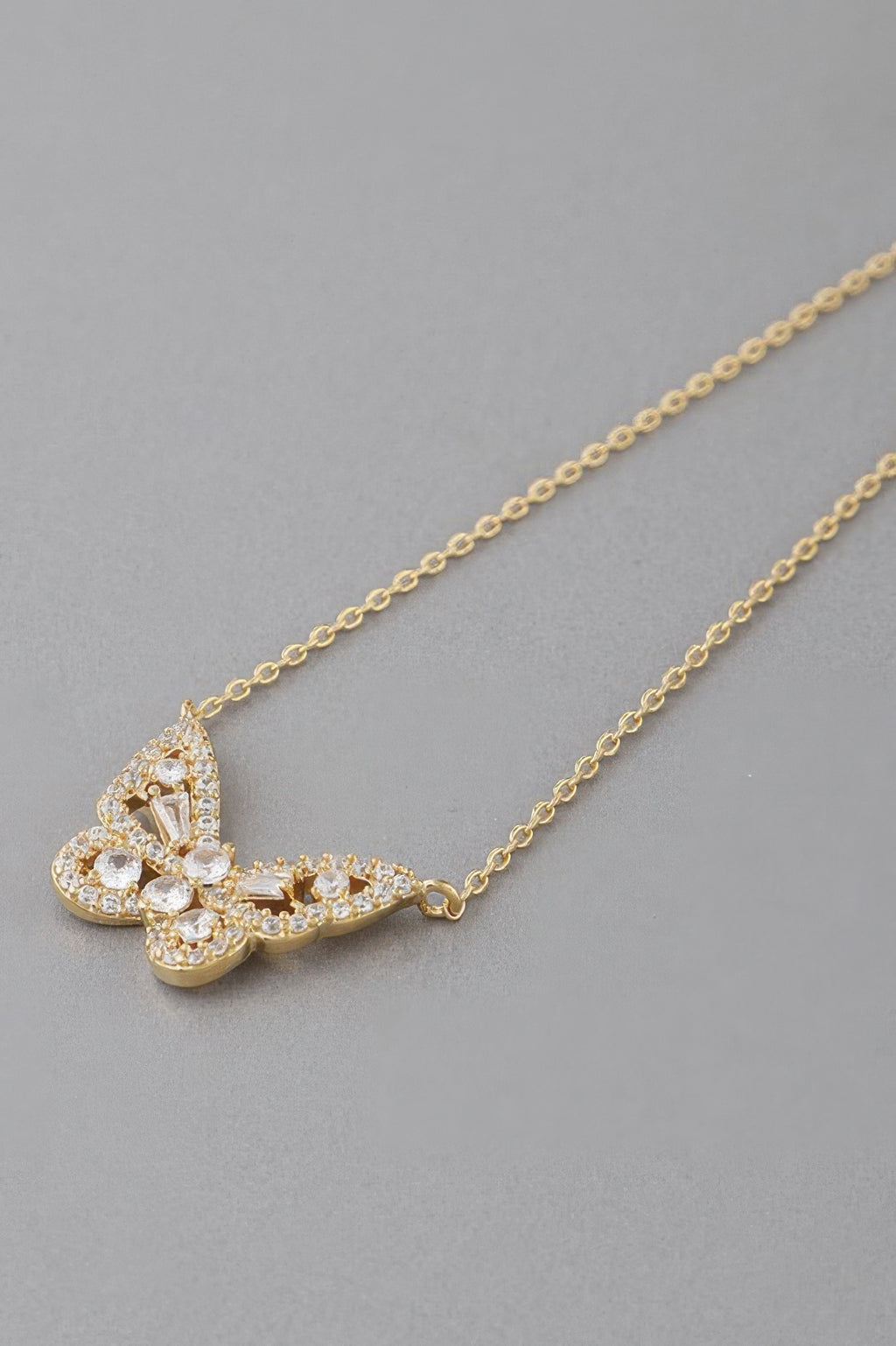 Clear rhinestone butterfly pendant on gold chain, close-up detail
