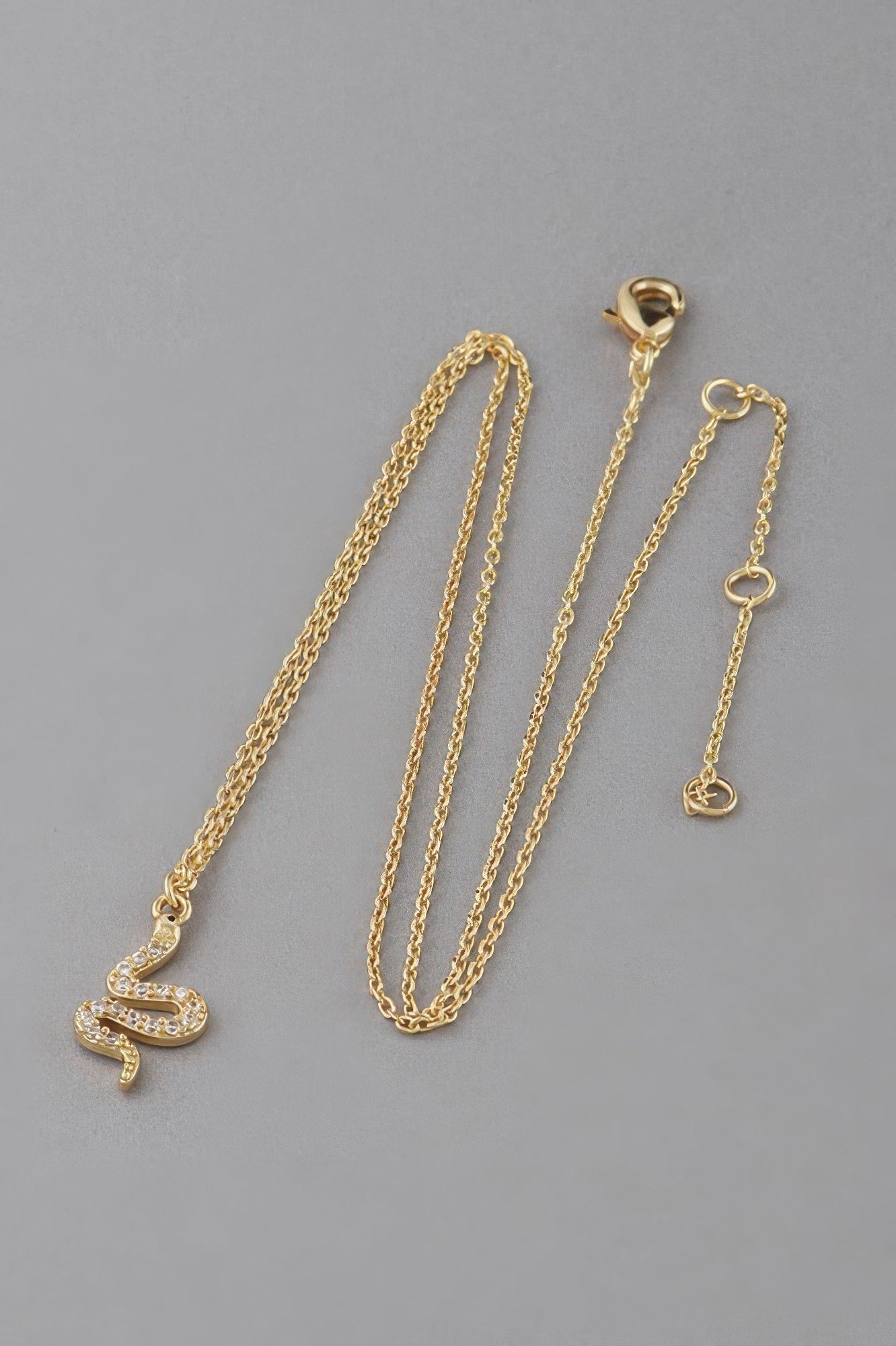 Gold-tone rhinestone snake pendant necklace with adjustable chain links and clasp