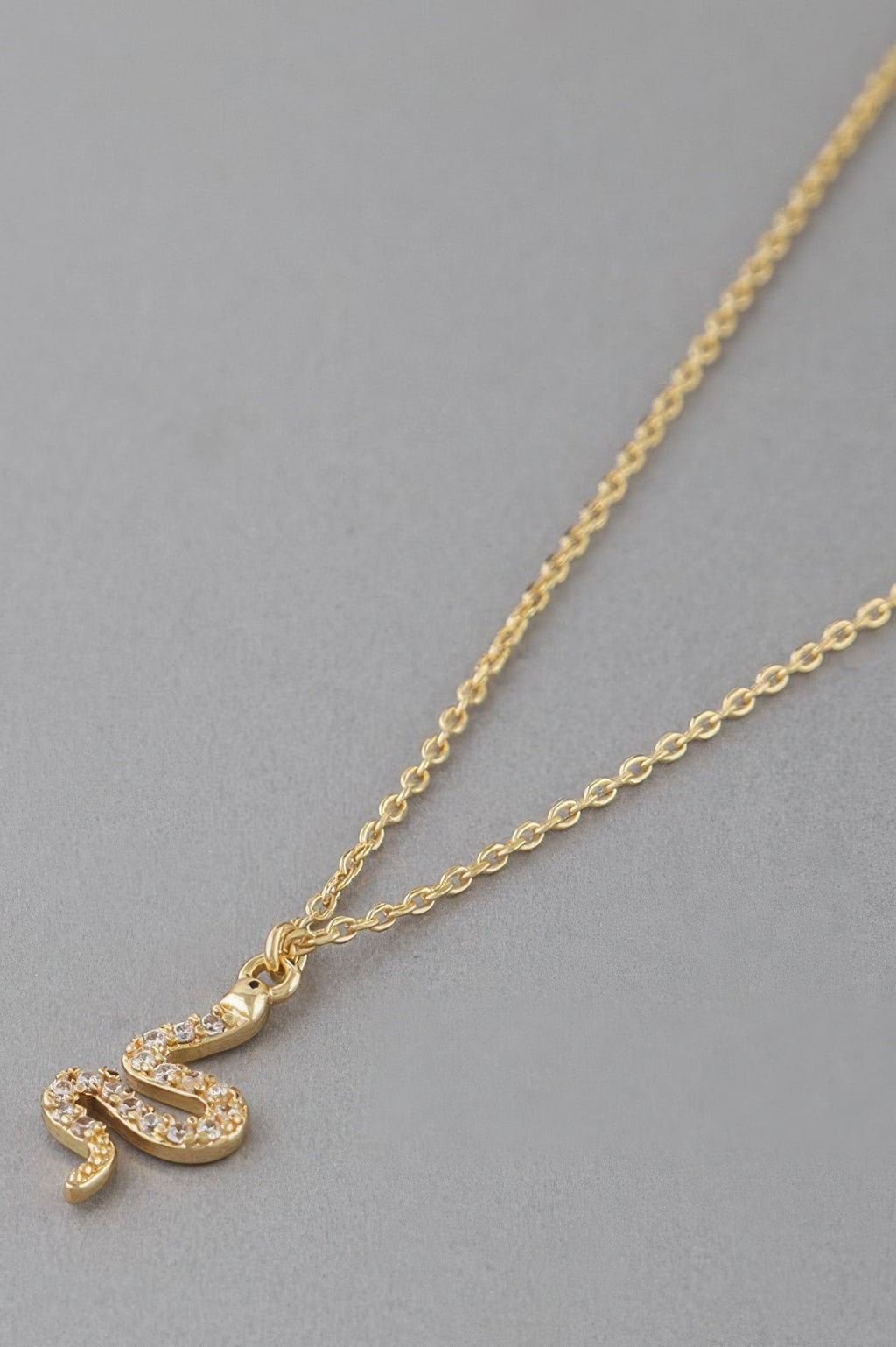 Close-up of gold rhinestone snake pendant on a fine chain