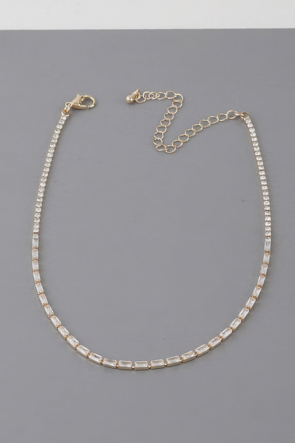 Gold-toned cubic crystal tennis-style necklace with adjustable chain and round clasp