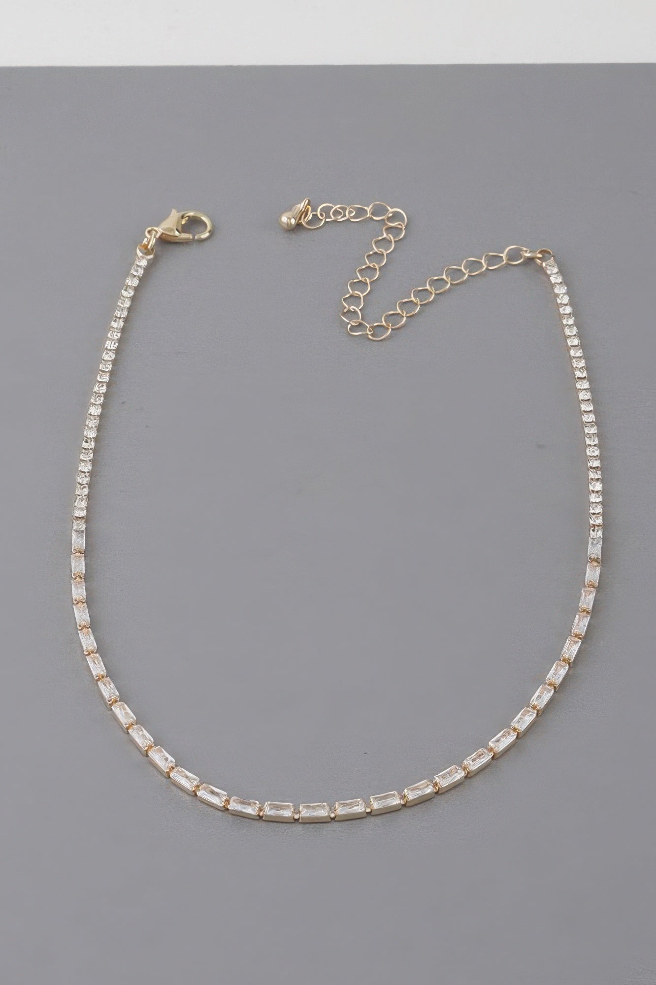 Gold-toned cubic crystal tennis-style necklace with adjustable chain and round clasp