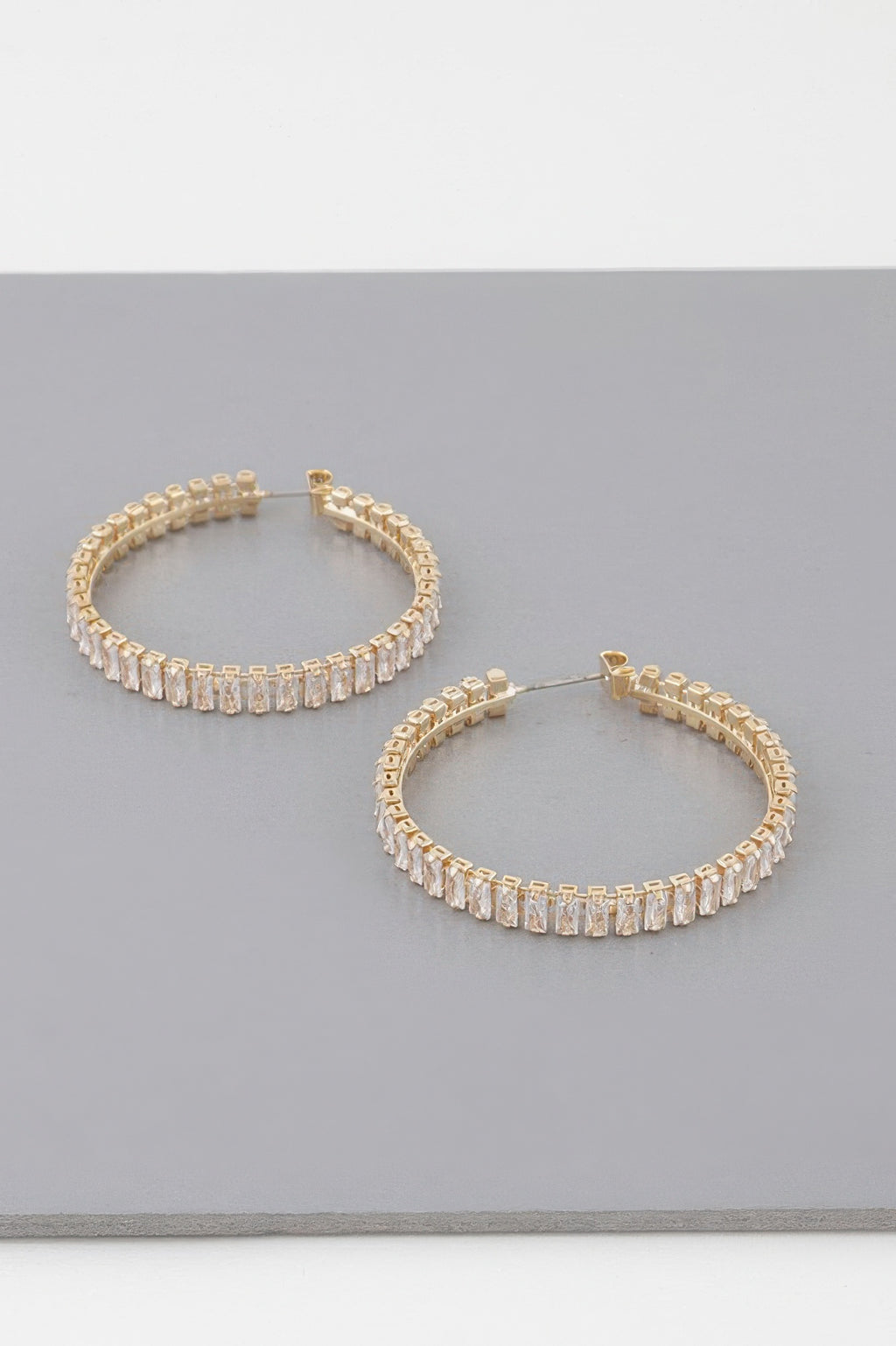Gold-tone hoop earrings with sparkling baguette crystals, front view
