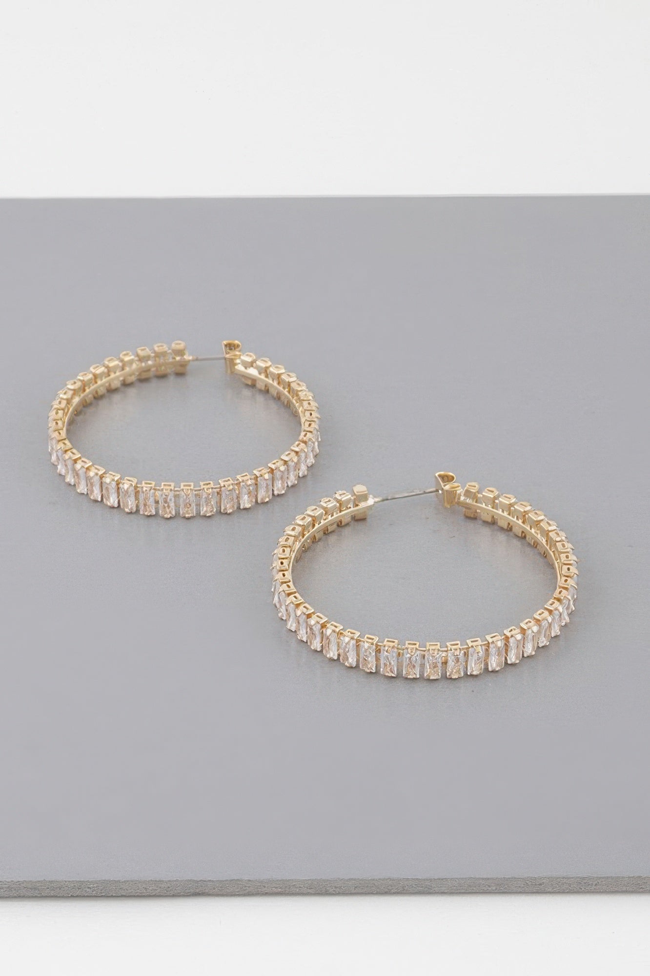 Gold-tone hoop earrings with sparkling baguette crystals, front view