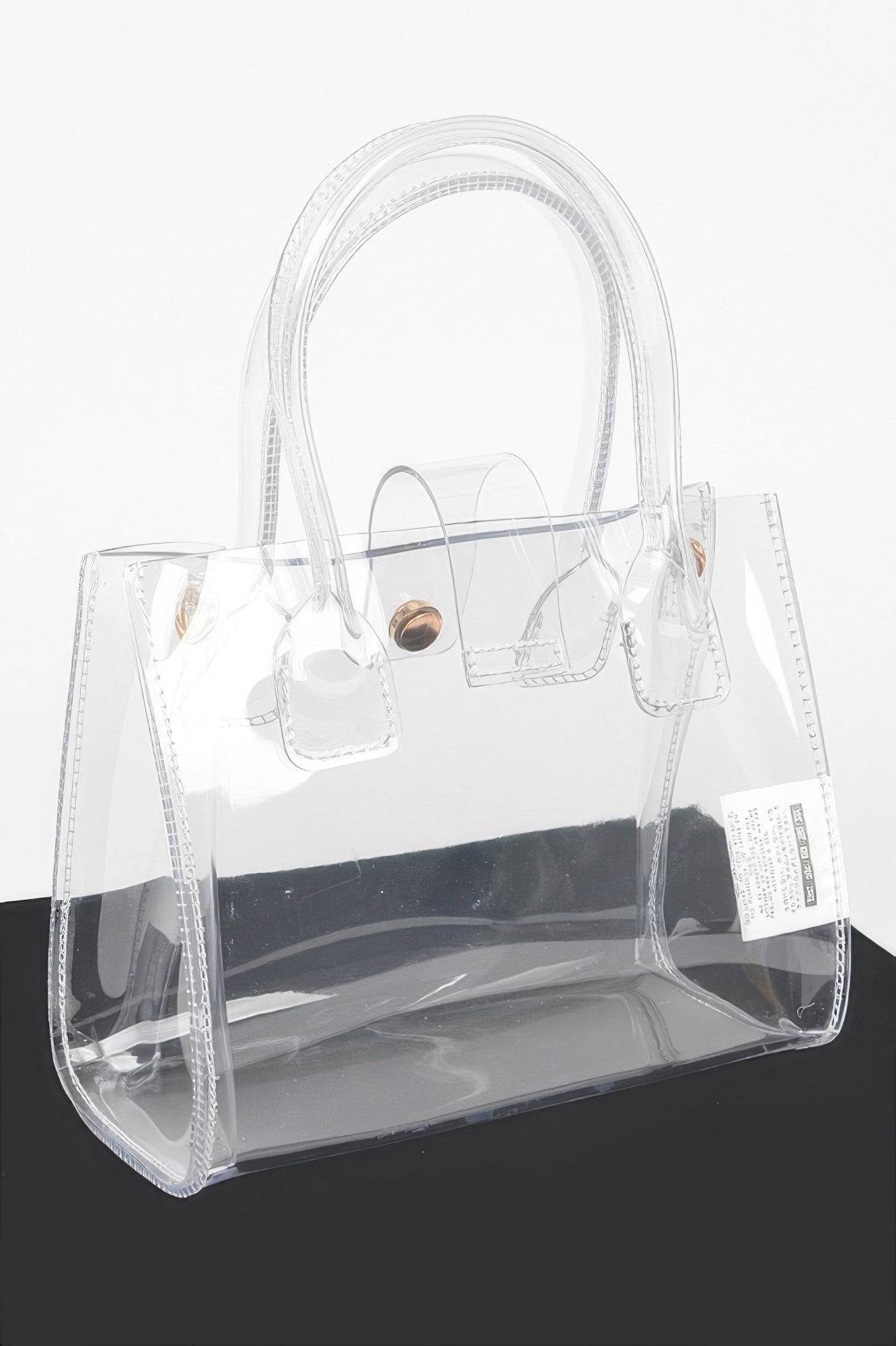 Clear crossbody bag with gold-tone closure, front pocket detailing, and top handles