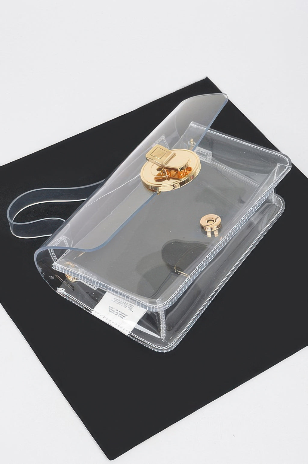Clear transparent tote bag with top handle, gold turn-lock clasp, and strap loops