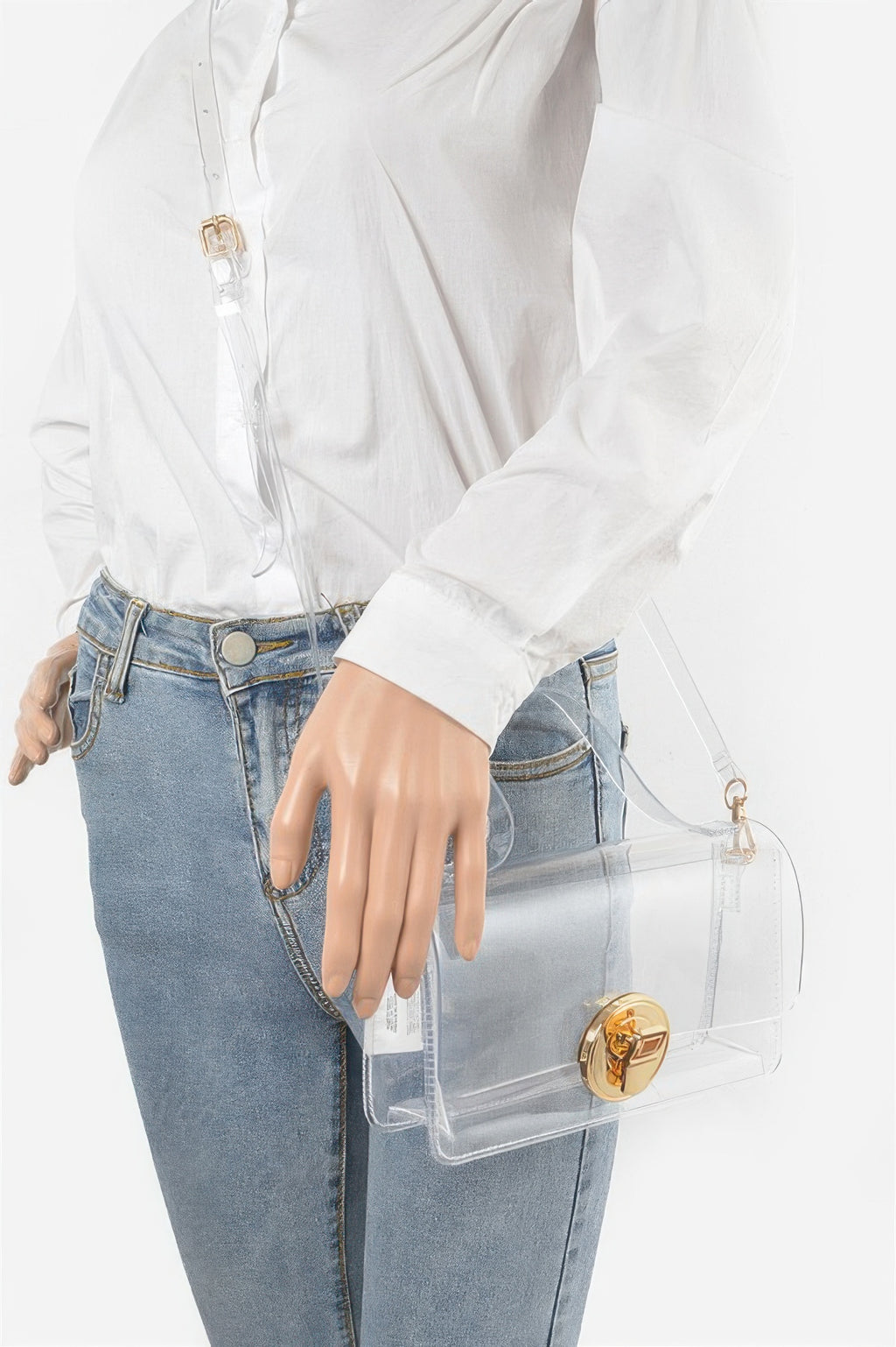 Transparent top-handle bag held on a clear strap with gold front clasp