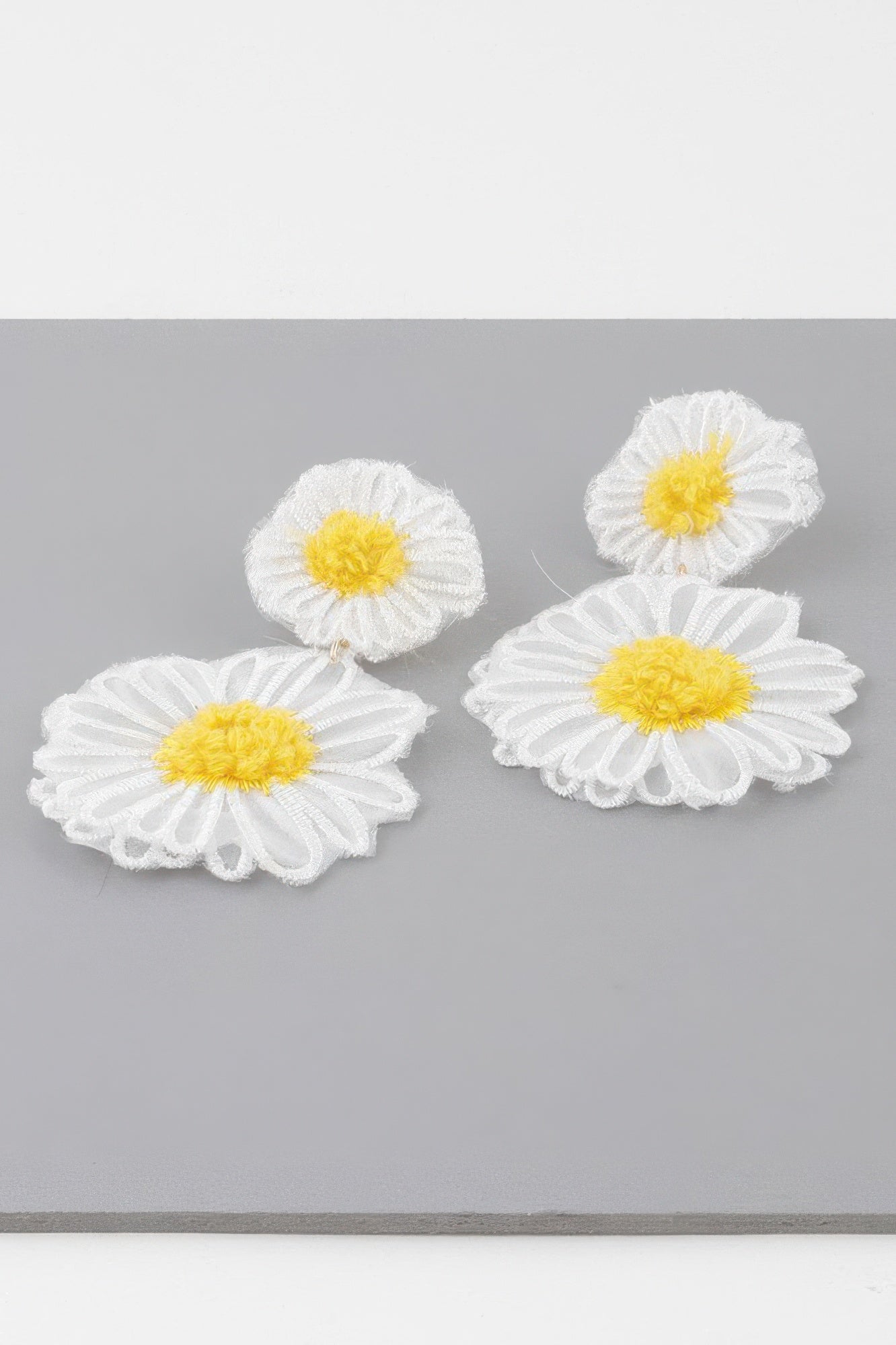 White fabric daisy flower earrings with yellow centers, layered petals, dangling style