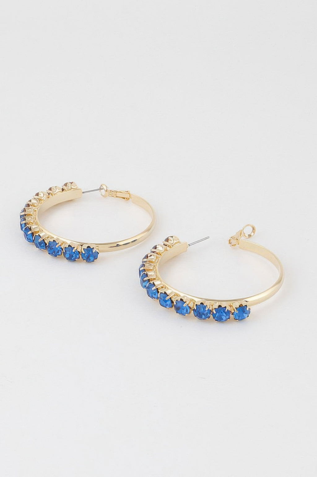 Pair of gold half-hoop earrings with blue stone trim and round hoop backs