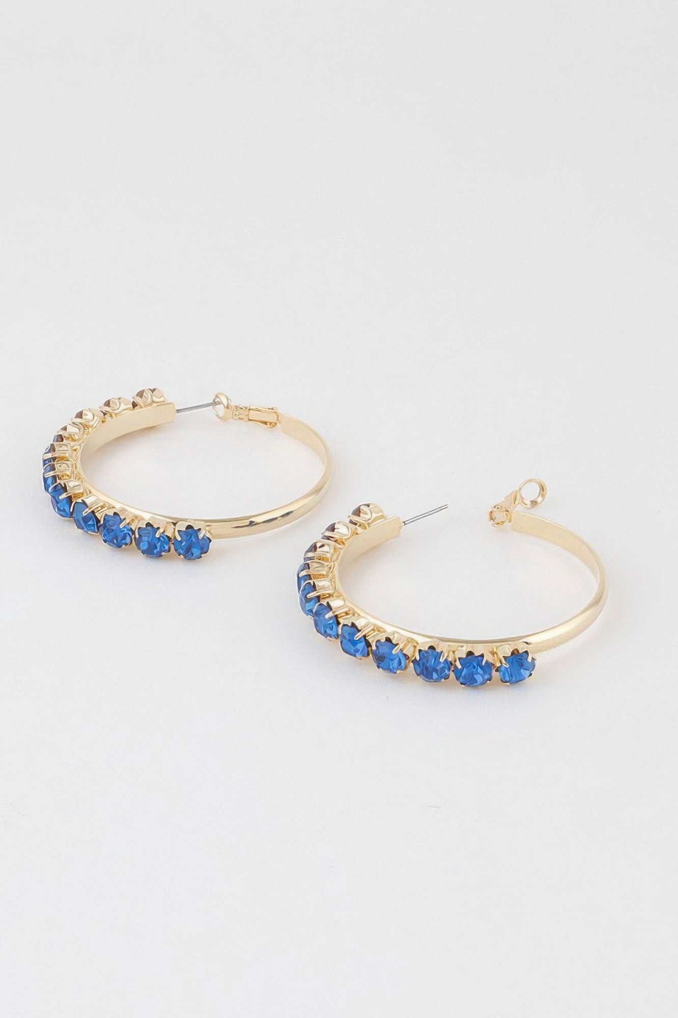 Pair of gold half-hoop earrings with blue stone trim and round hoop backs