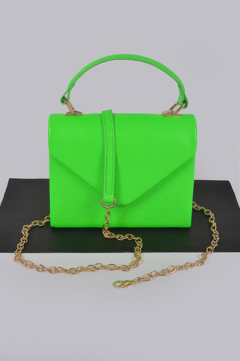 Neon green boxy clutch with top handle, flap front, and gold chain strap