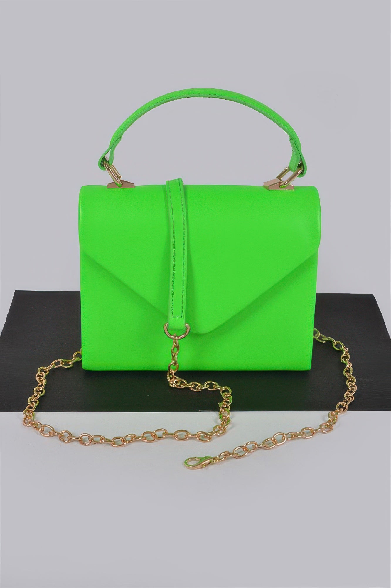 Neon green boxy clutch with top handle, flap front, and gold chain strap