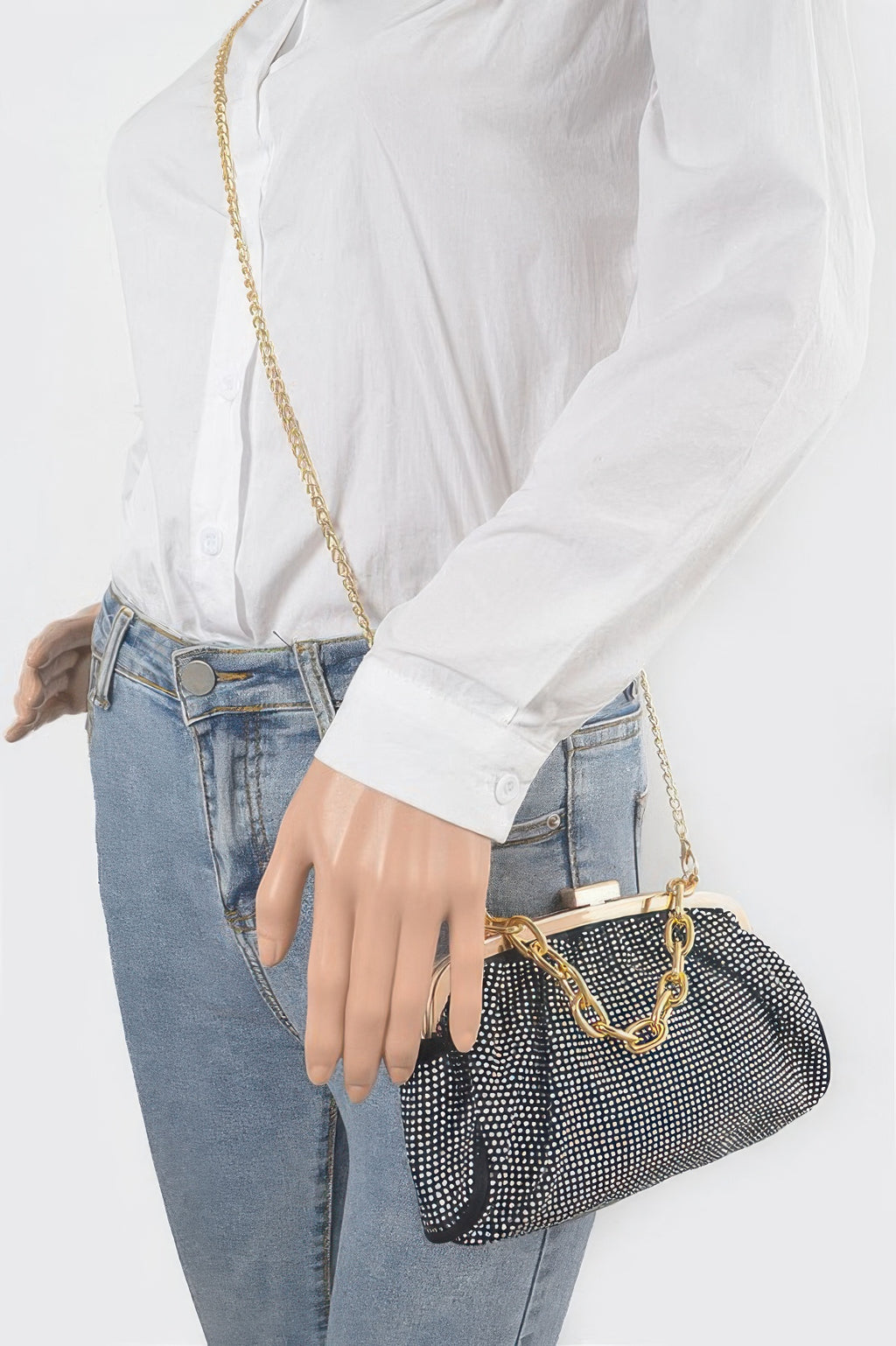 Black Hotfix Party Clutch on shoulder with gold chain strap over studded fabric.