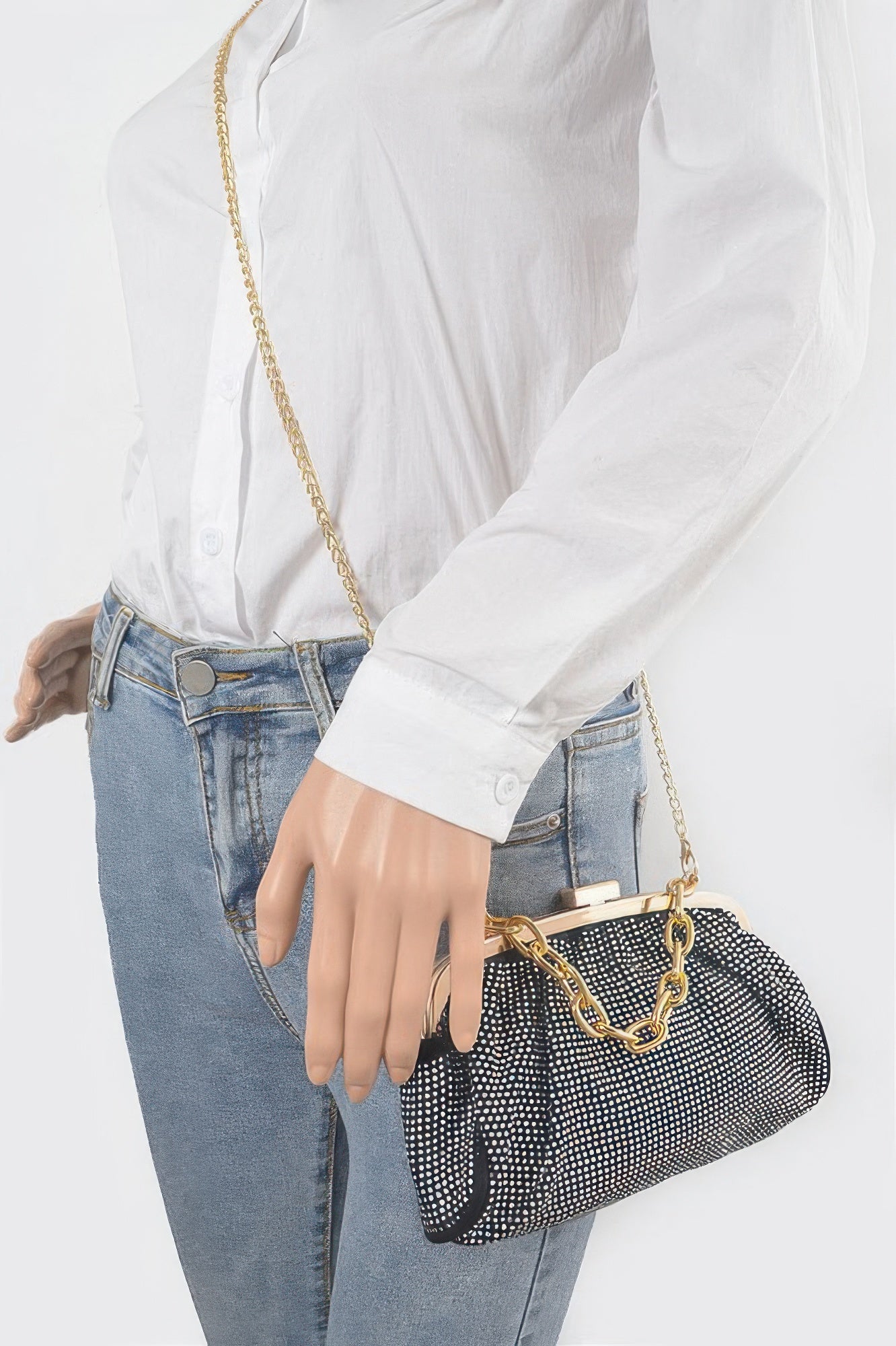 Black Hotfix Party Clutch on shoulder with gold chain strap over studded fabric.