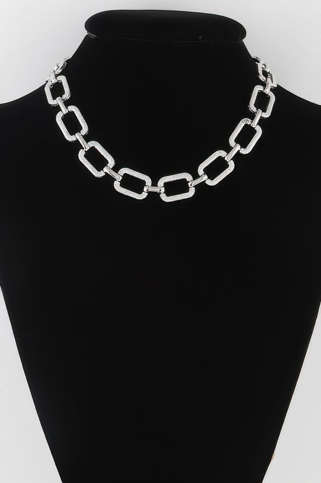 Silver textured link chain necklace on black mannequin